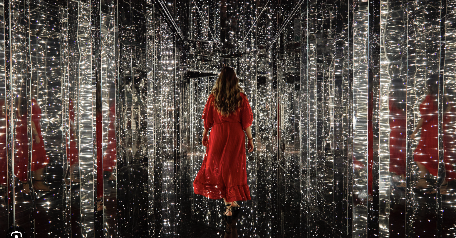 Virgin Voyages sparking hallway of the Manor with a woman with brown hair and red dress is walking. 