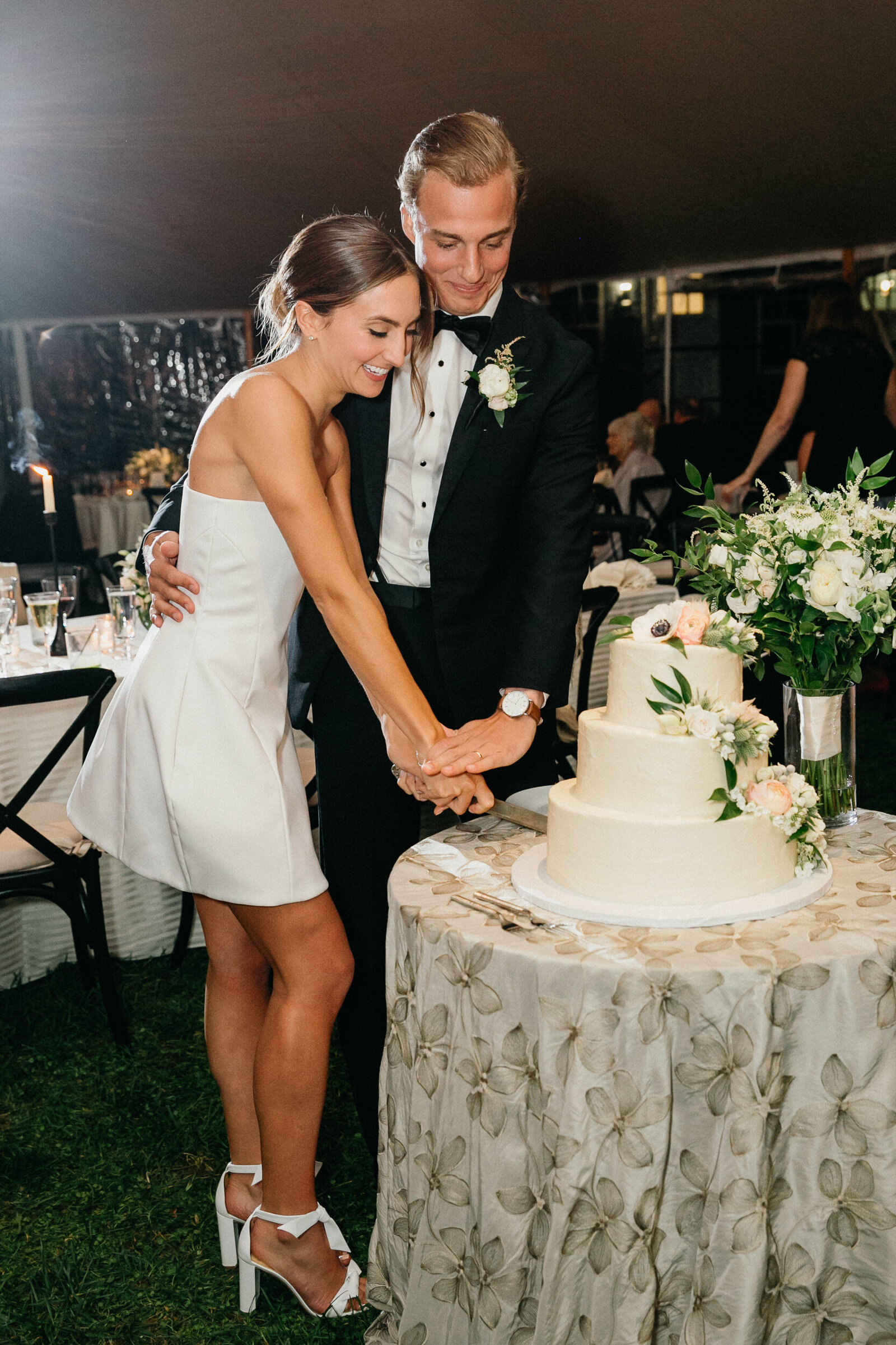 Bride and groom cutting wedding cake under the lights at a Radnor Hunt Club wedding.