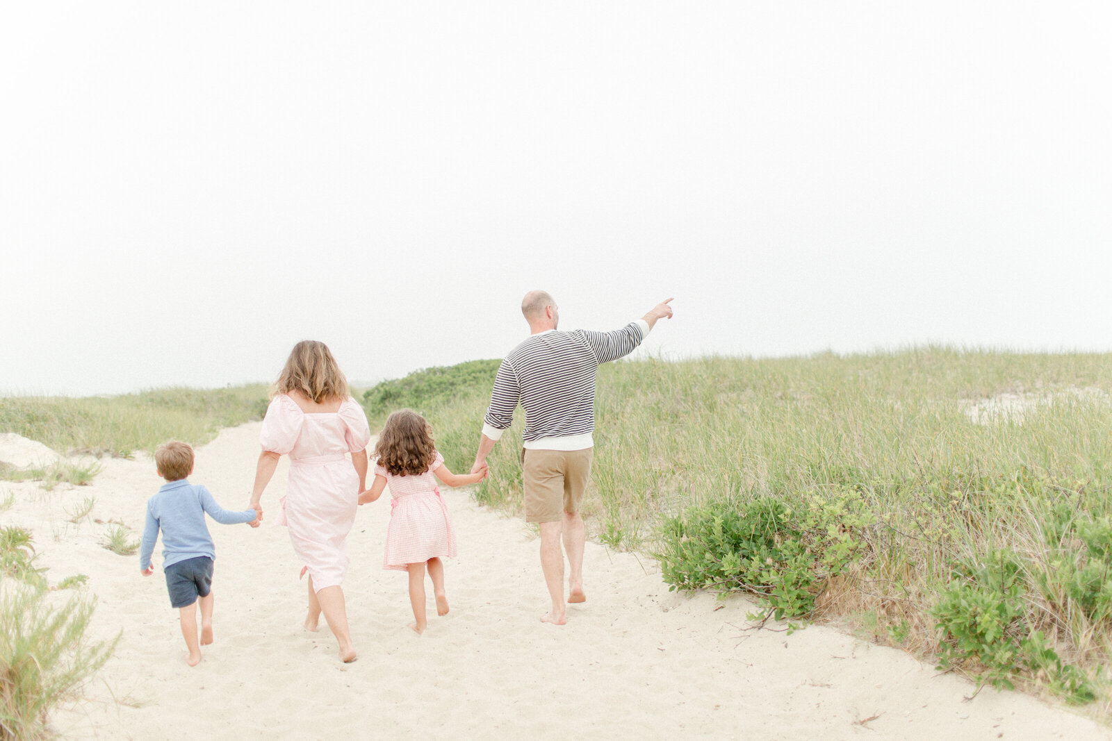 A young family of four walking on the beach during photo session with Cape Cod photographer Corinne Isabelle