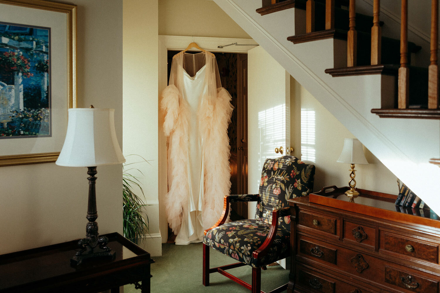 Bridal gown hanging under a staircase in a cozy setting