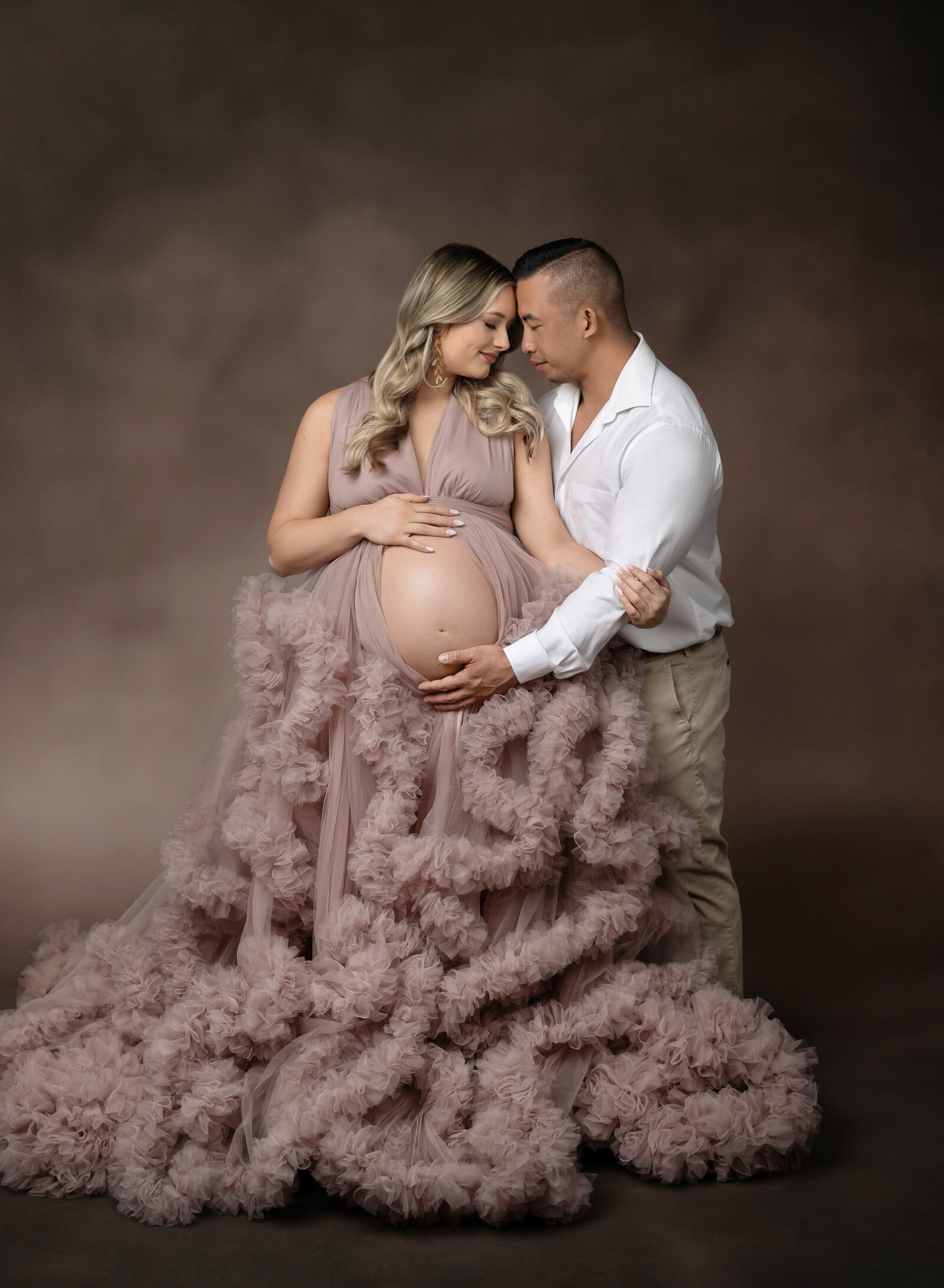 Mom and Dad cuddling and feeling baby kick. Photo taken at Atlanta Photo studio in Woodstock, GA.