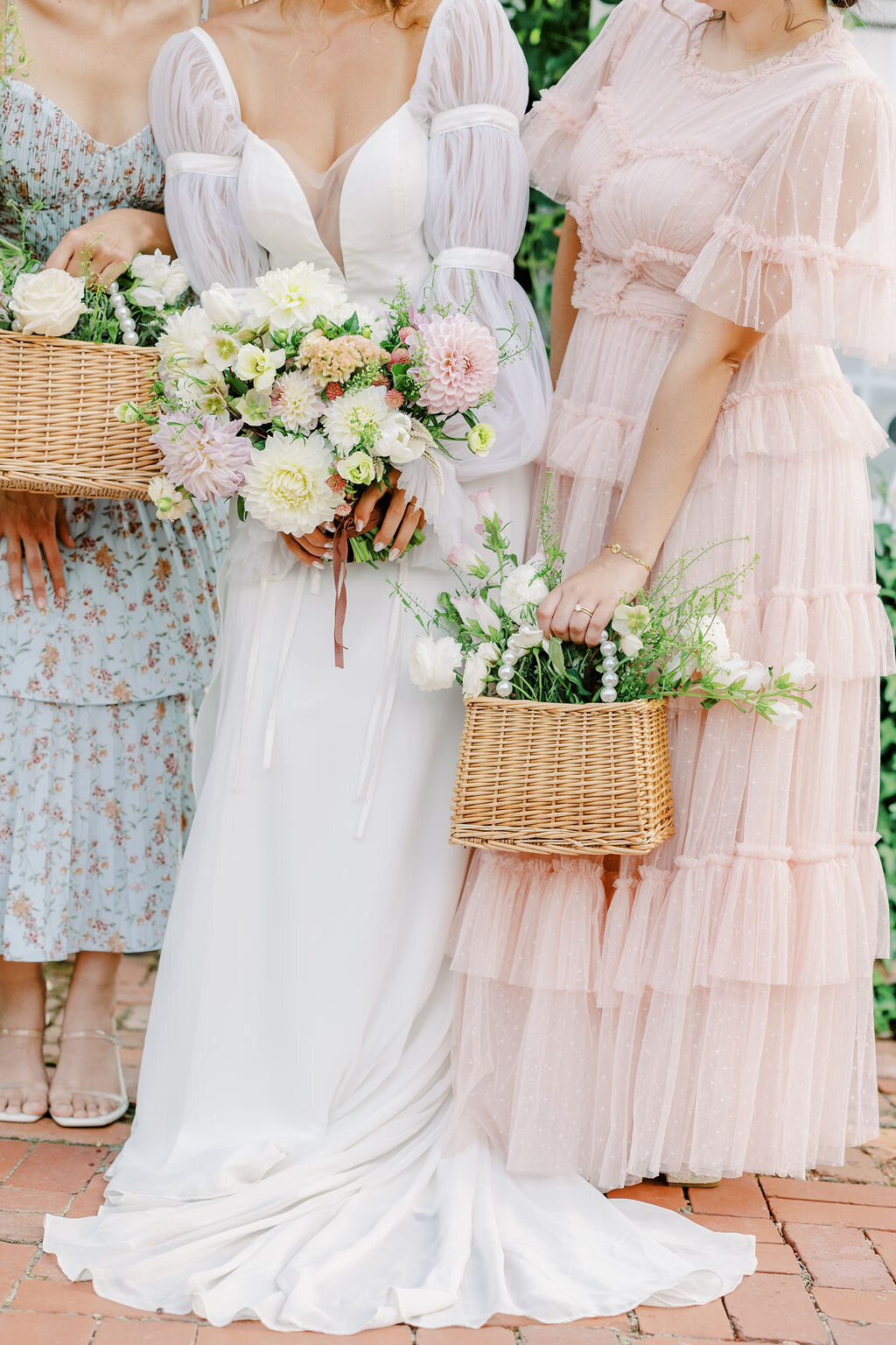 Bride with pink bouquet stands next to bridesmaids outside at the Wildflower