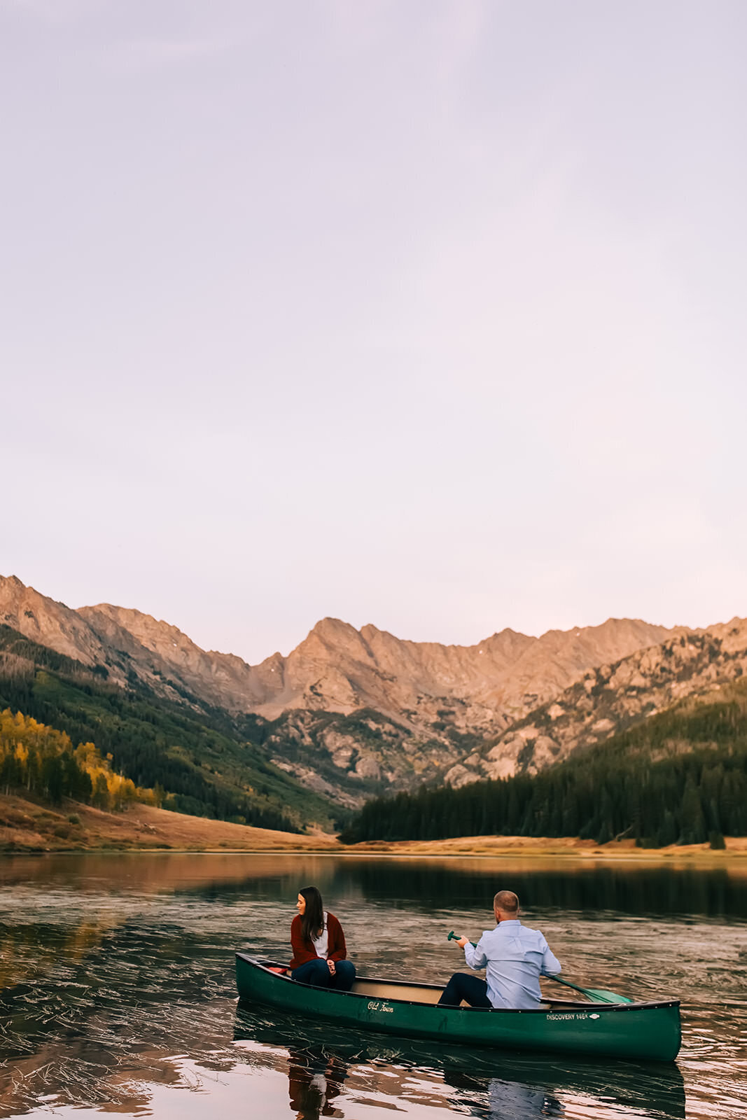 Couple canoeing in Colorado mountain alpine lake during engagement photos