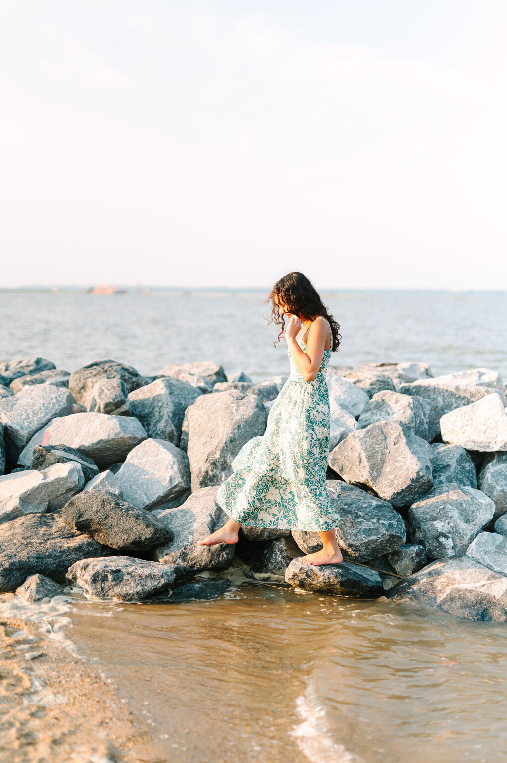 a young woman walking on rocks at the beach