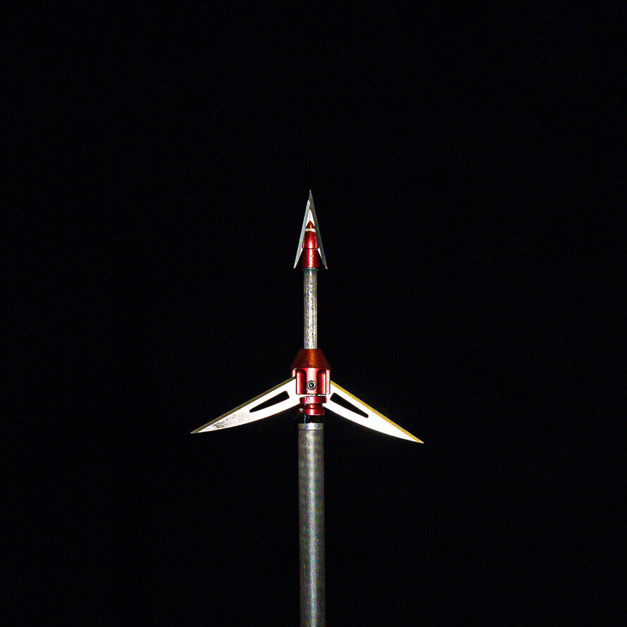 Close up shot of a SABO broadhead arrow on a black background.