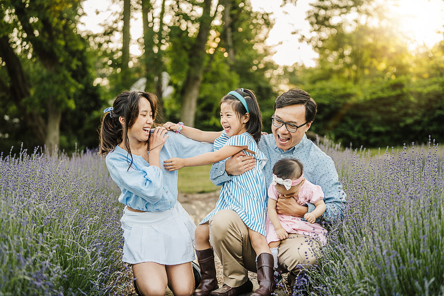 dad laughs with three daughters in a field of lavender
