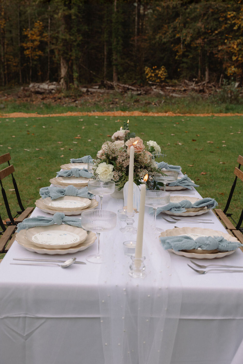 Outdoor tablescape featuring candles, florals, and blue linens
