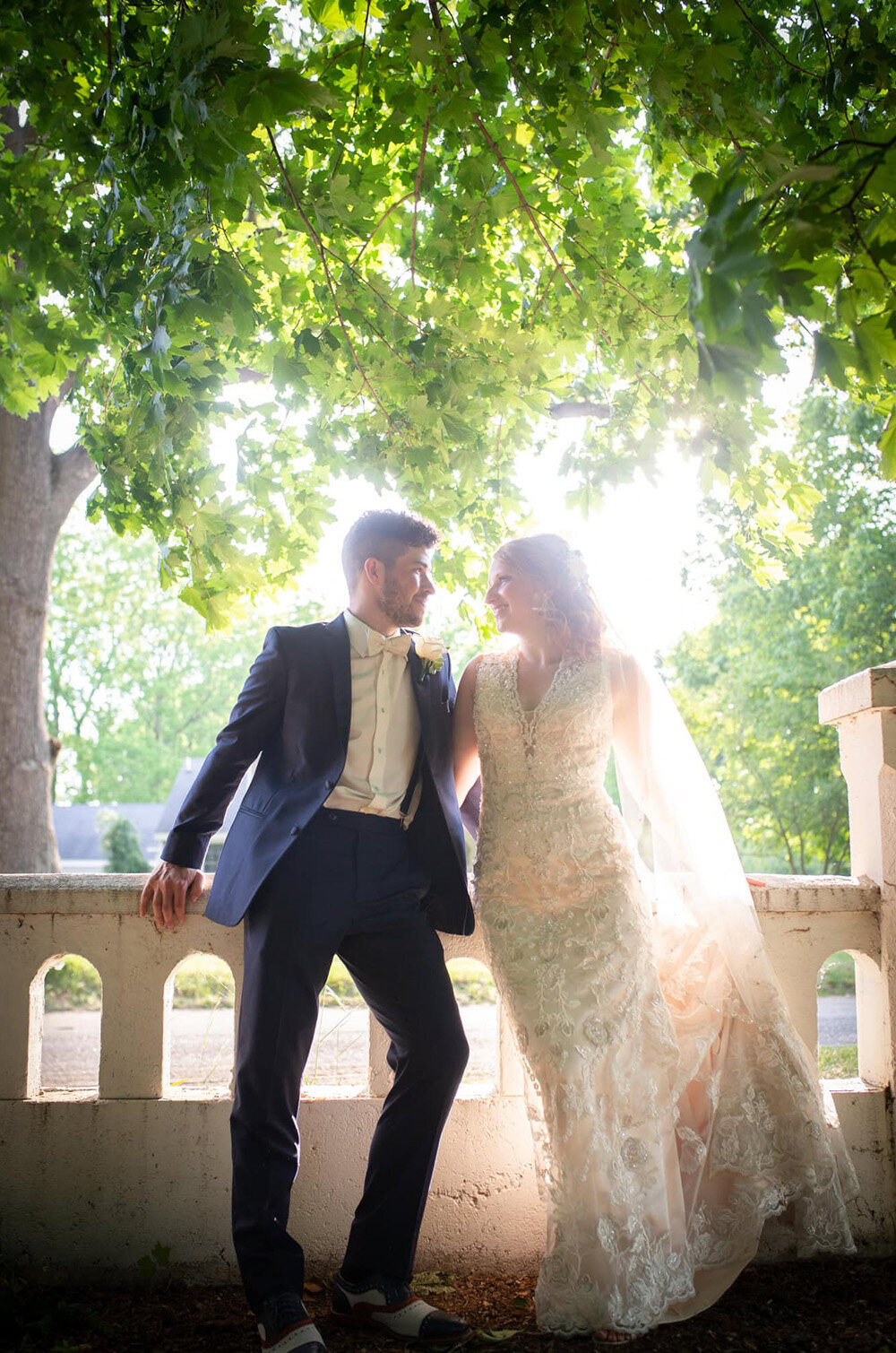 bride and groom look at each other in front of sunshine through trees
