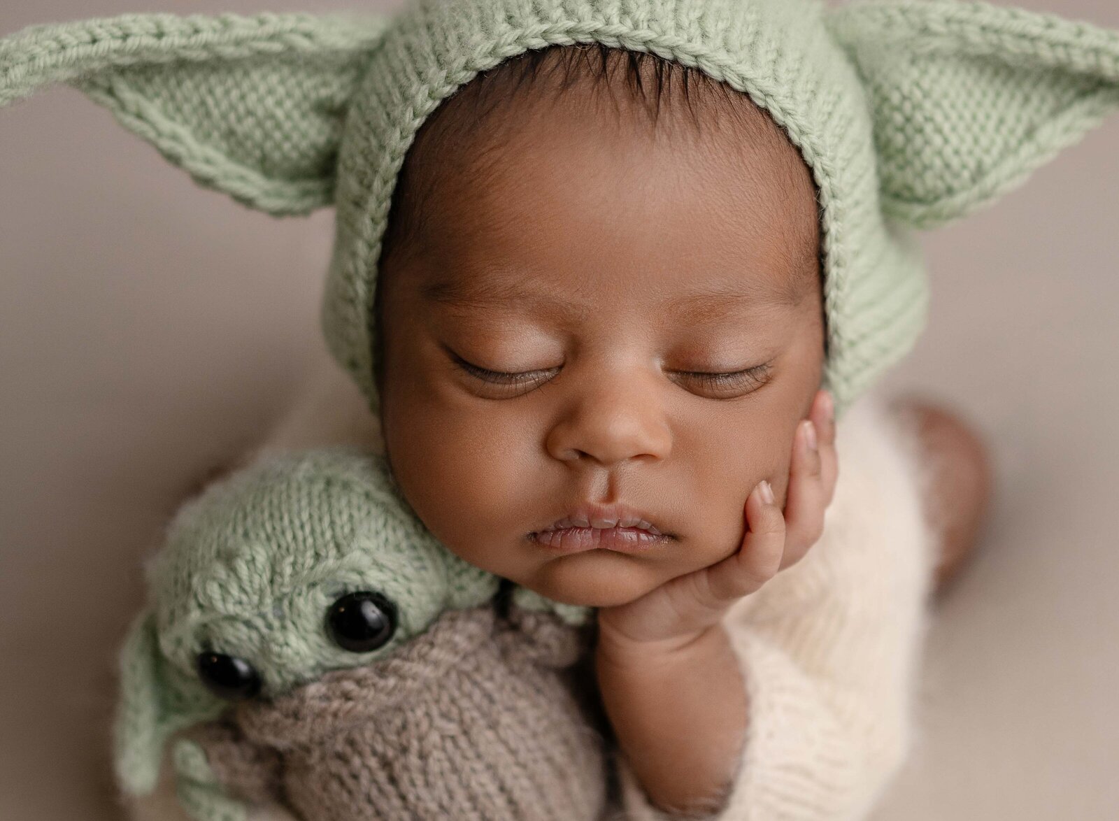 Baby with yoda bonnet and holding yoda stuffed animal. Newborn Photography session photographed at Jenni Nikki's photo studio in Marietta, GA.