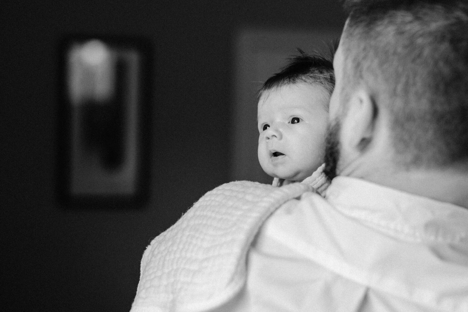 A newborn baby looks over dad's shoulder as she tries to see out the window in Tampa