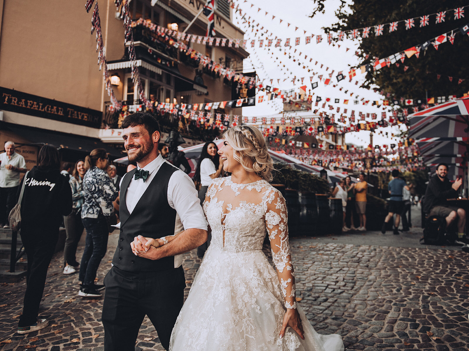 Bride and groom walking underneath bunting at Trafalgar Tavern in London