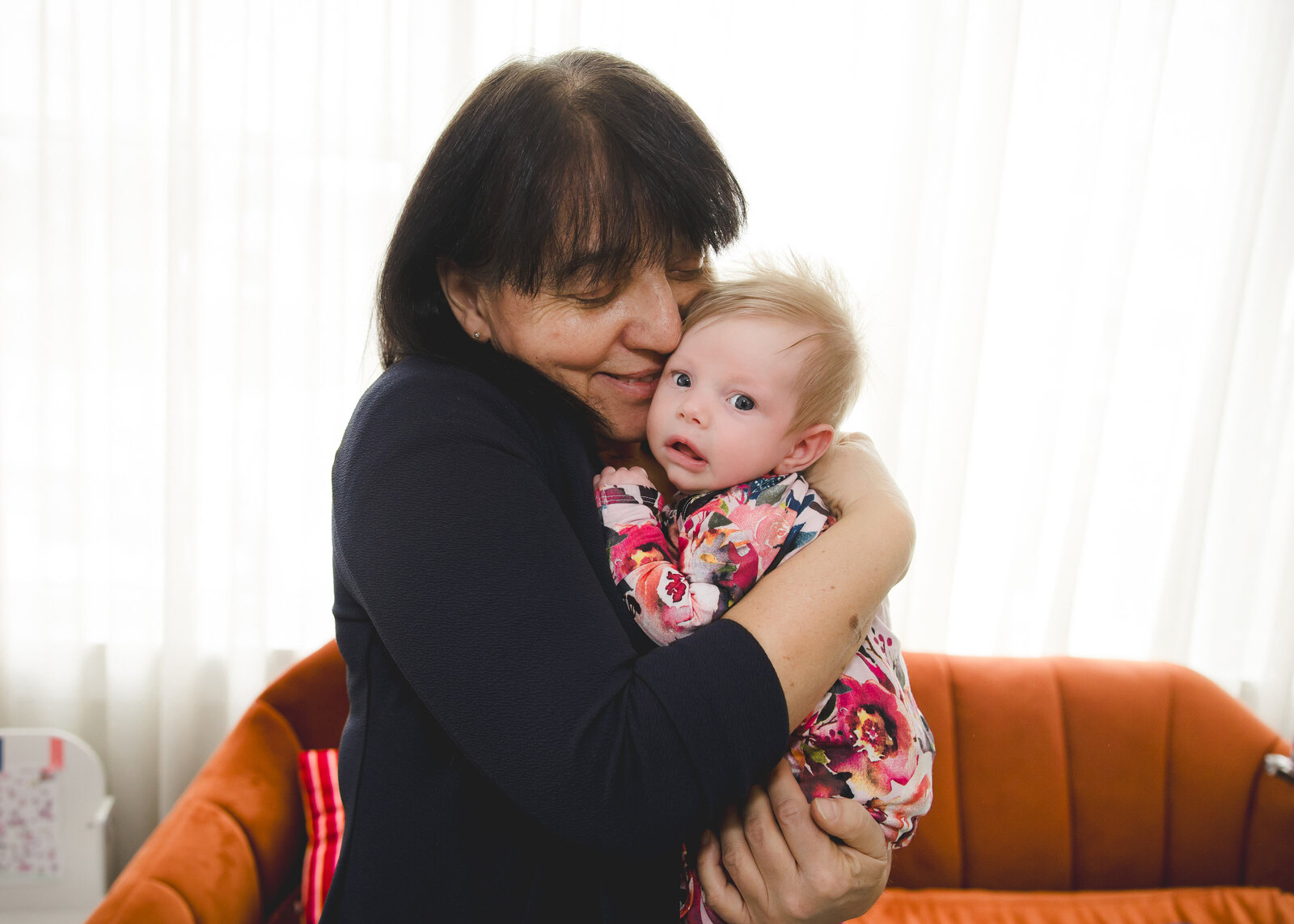 Lifestyle portrait of a grandmother hugging her grandchild.