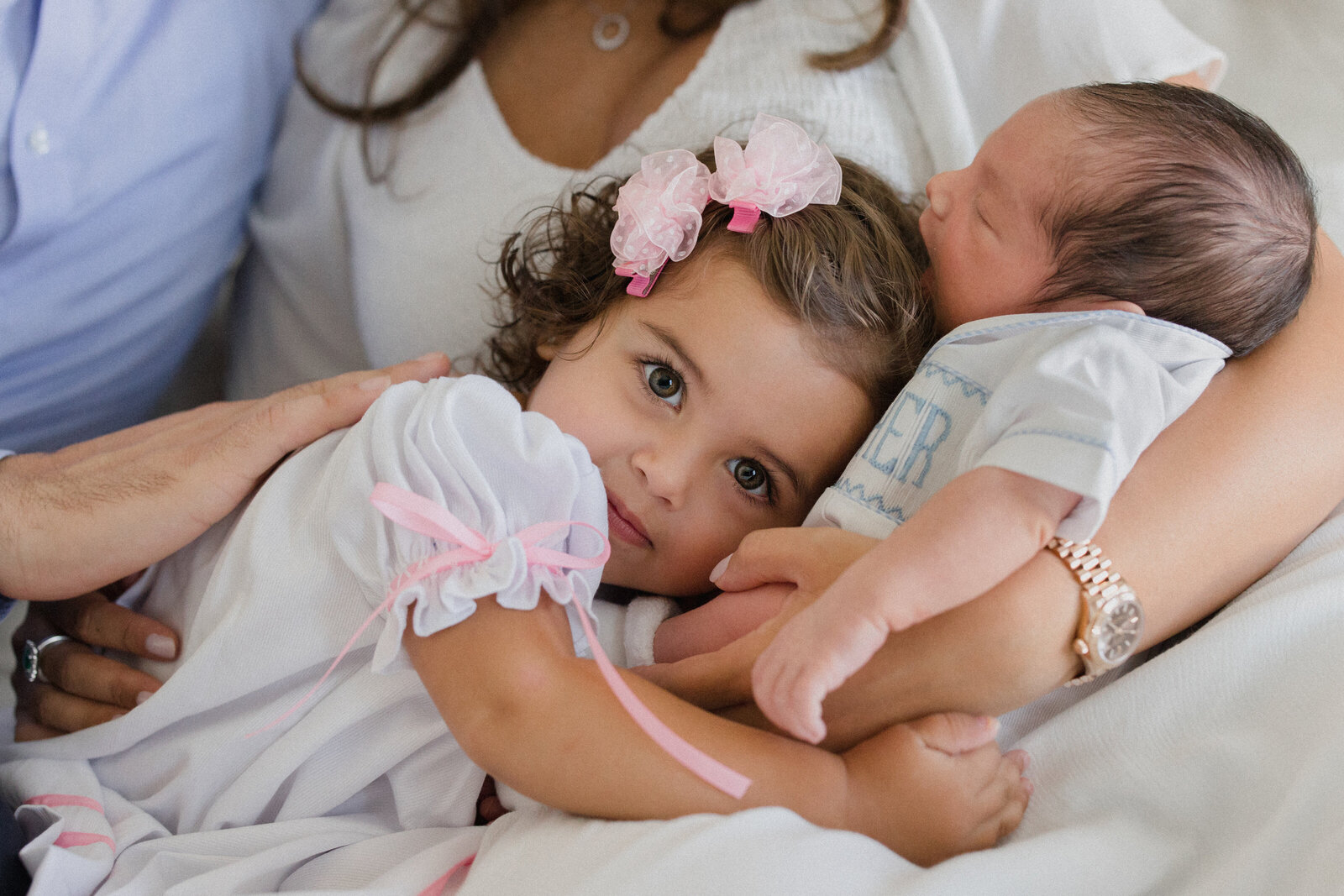 Little girl looks into camera while snuggling new baby brother at home in Riverview