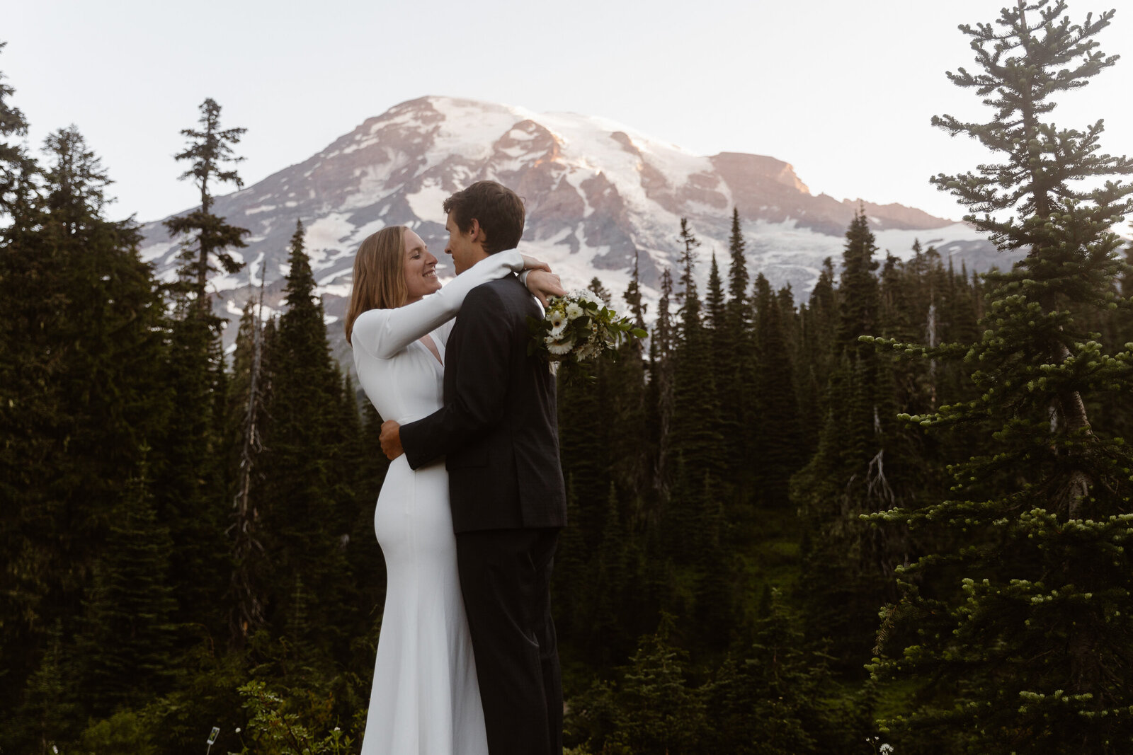 couple embraces in front of Mount Rainier at sunrise at Washington elopement