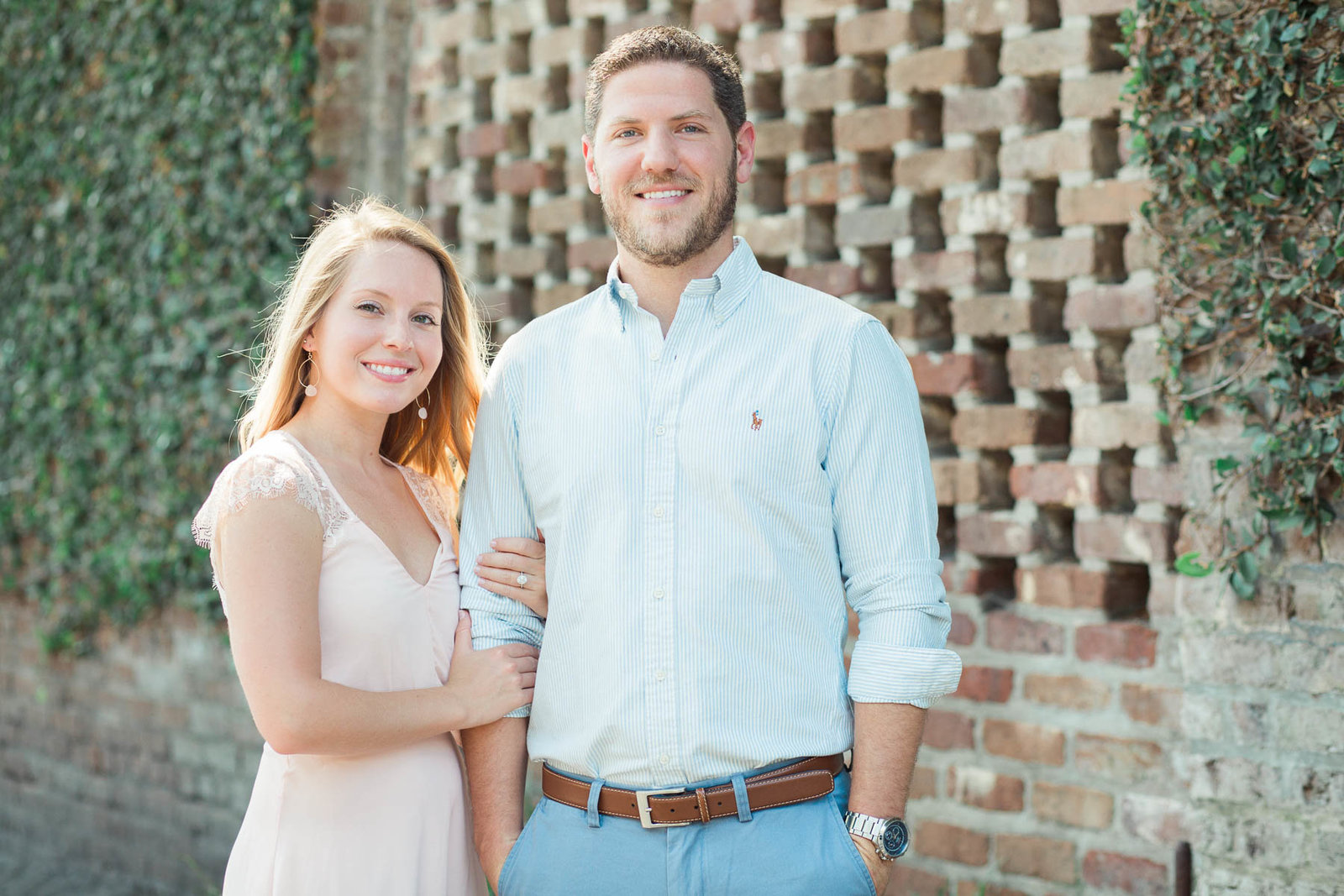 Engaged couple pose in front of red brick and ivy, Downtown Charleston, South Carolina