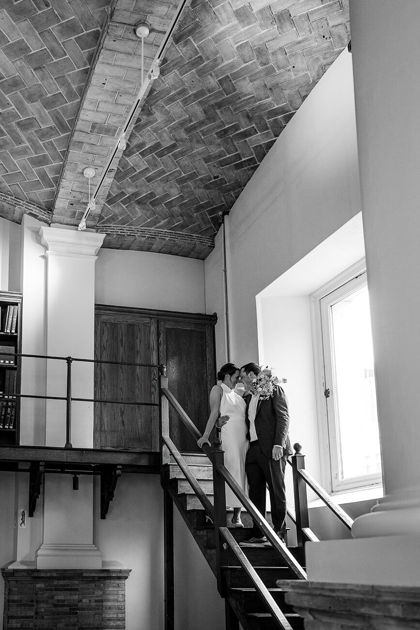 couple stands forehead to forehead in the stairwell of boston public library