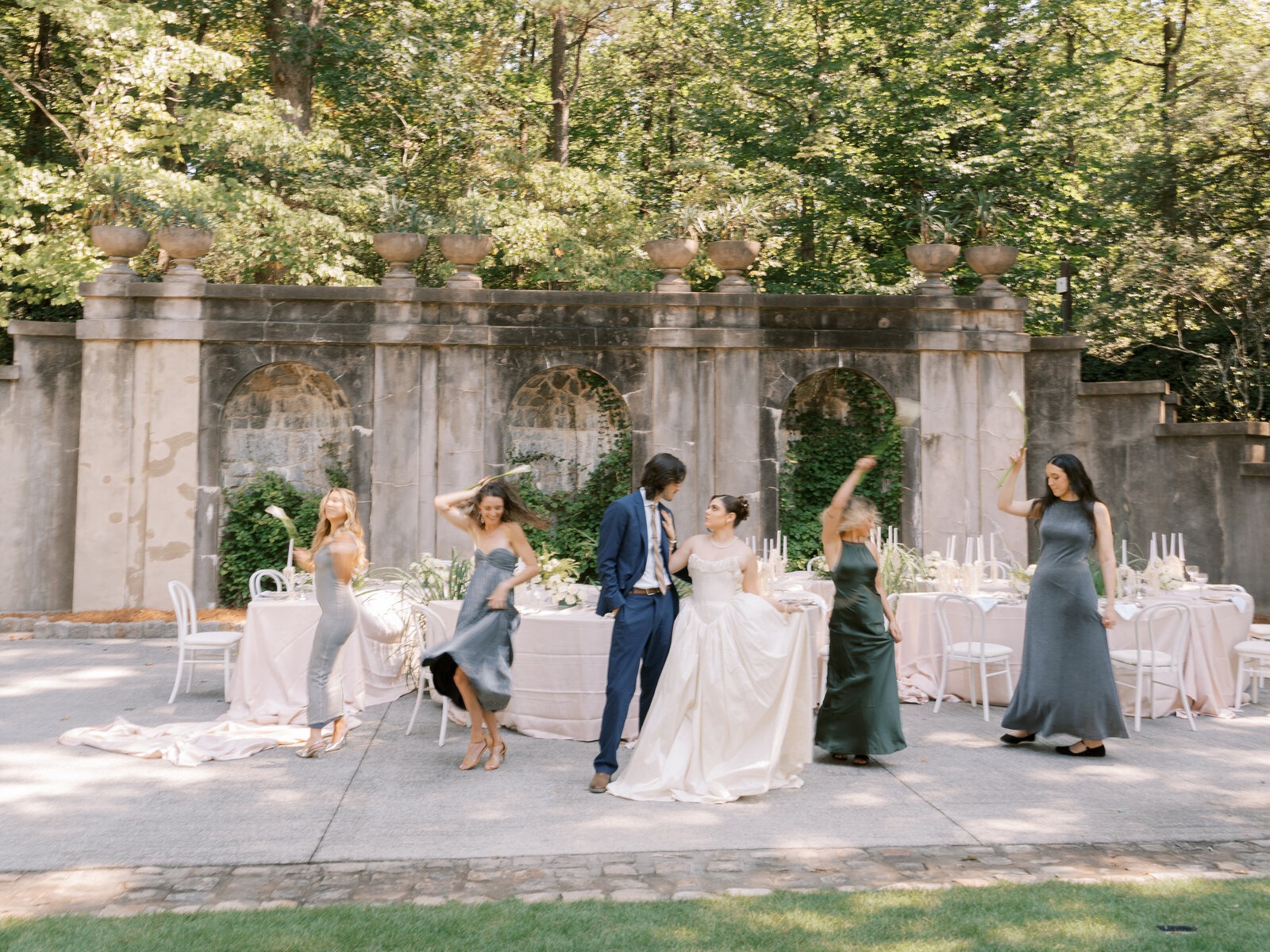 bridal party with bridesmaids dancing in front of reception table at swan house 