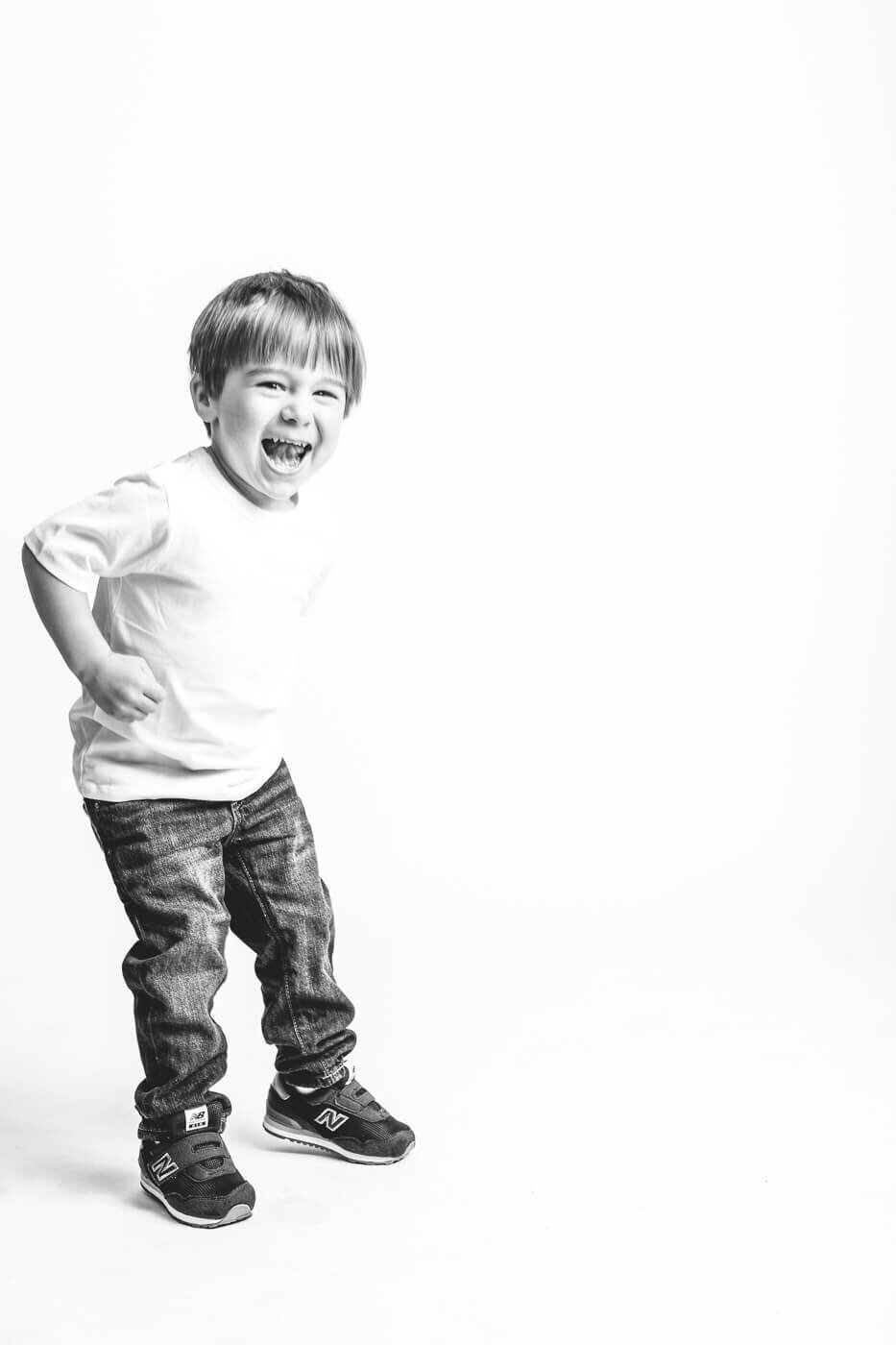Juvenile boy standing in funny pose while laughing