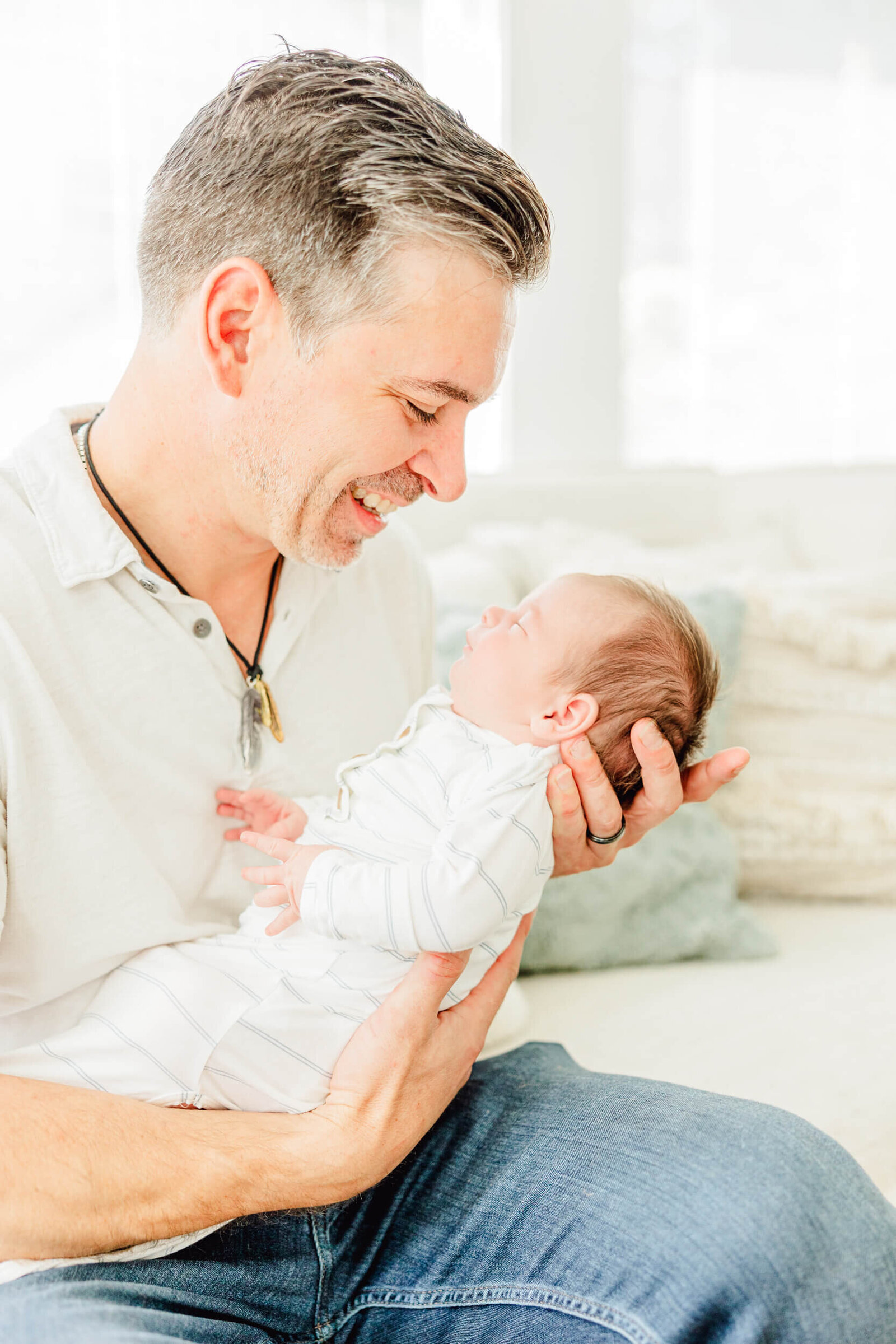 Dad smiles down at his newborn on a couch