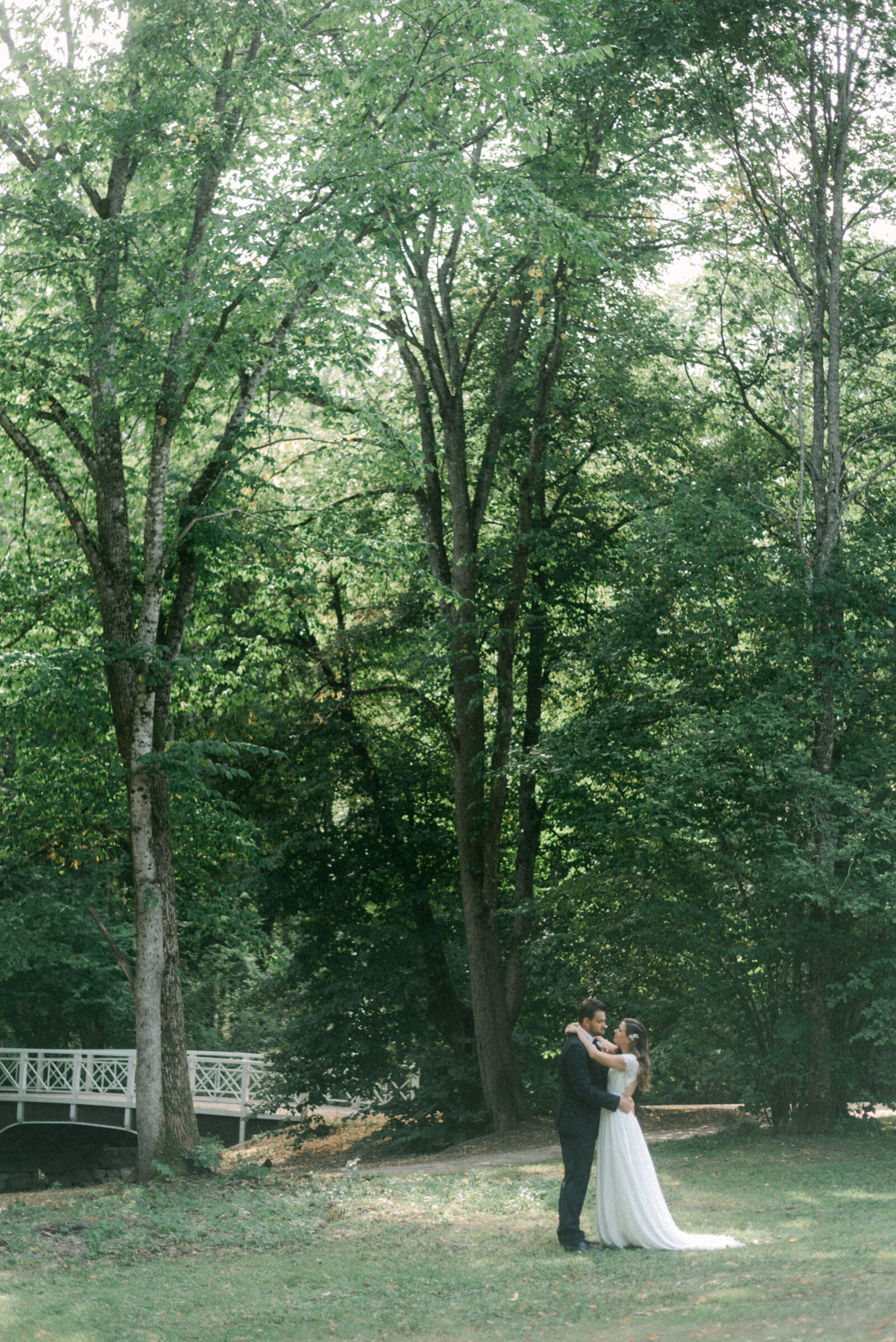 A wedding couple hugging in a park next to a bridge in summer during their wedding photo shoot with Nordic wedding photographer Hannika Gabrielsson.
