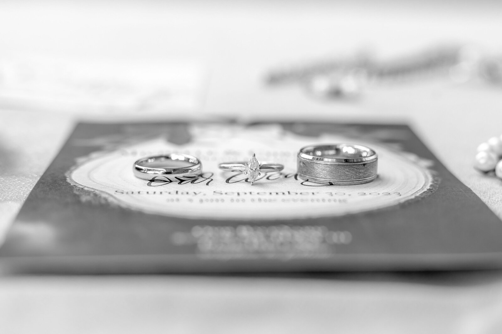 Elegant black and white photograph of wedding rings displayed on a beautifully designed invitation, highlighting the significance of love in North Carolina.