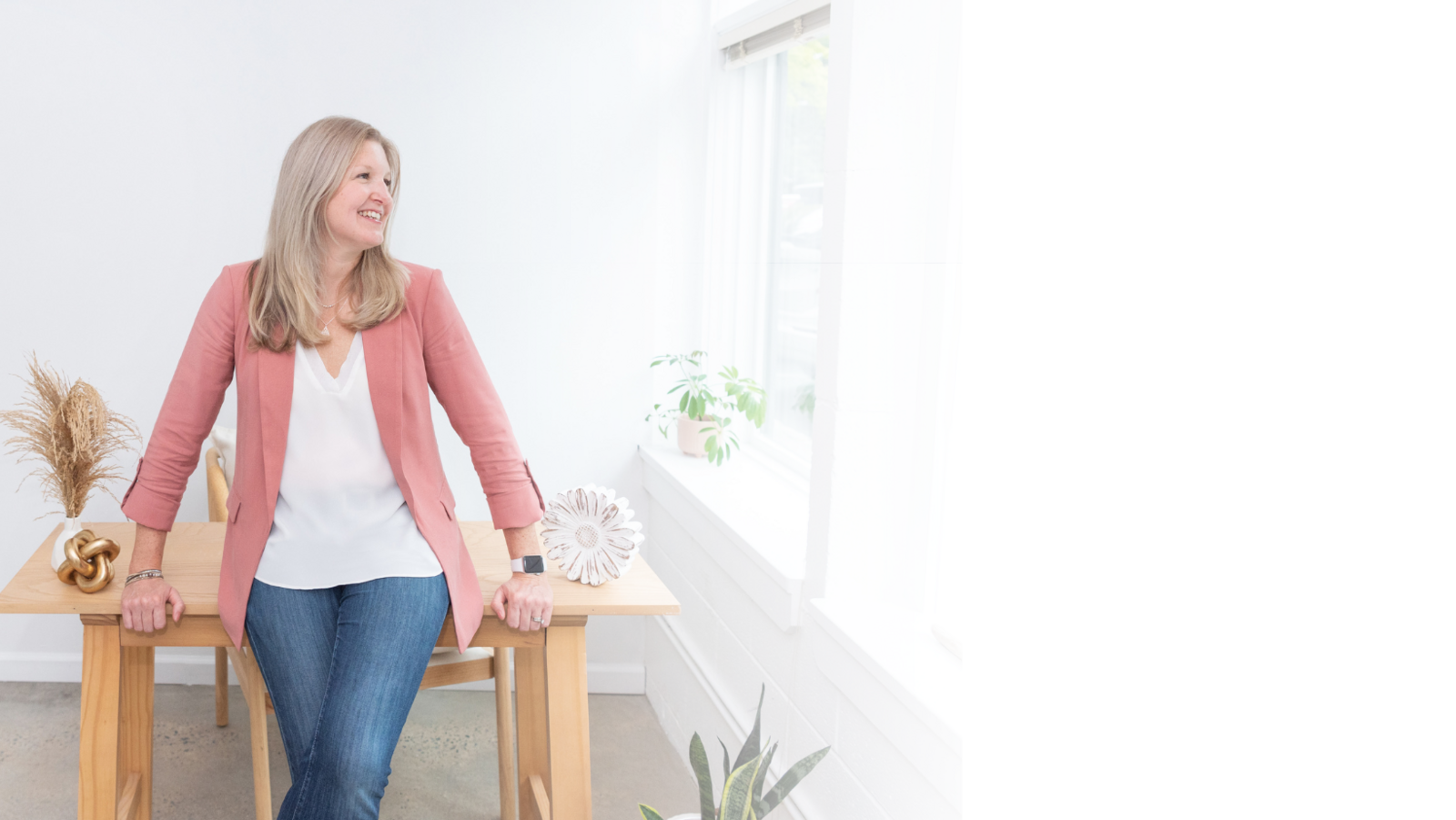 Maureen owner of the creative impact standing in front of desk looking to the right and smiling