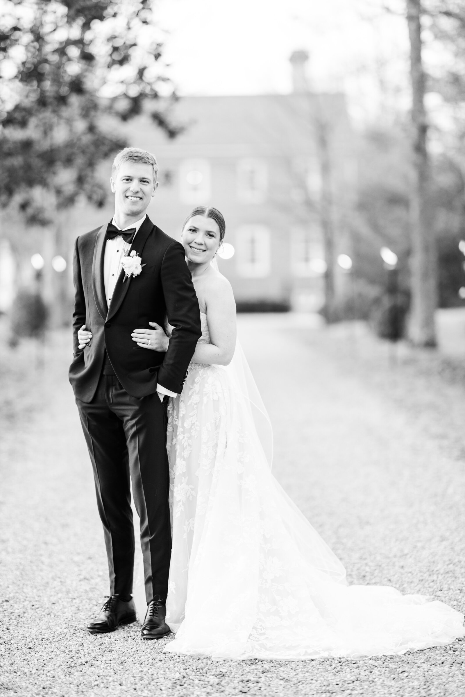 Bride wraps her arms around the groom from behind, a heartfelt embrace capturing deep love and joy in a timeless wedding moment.