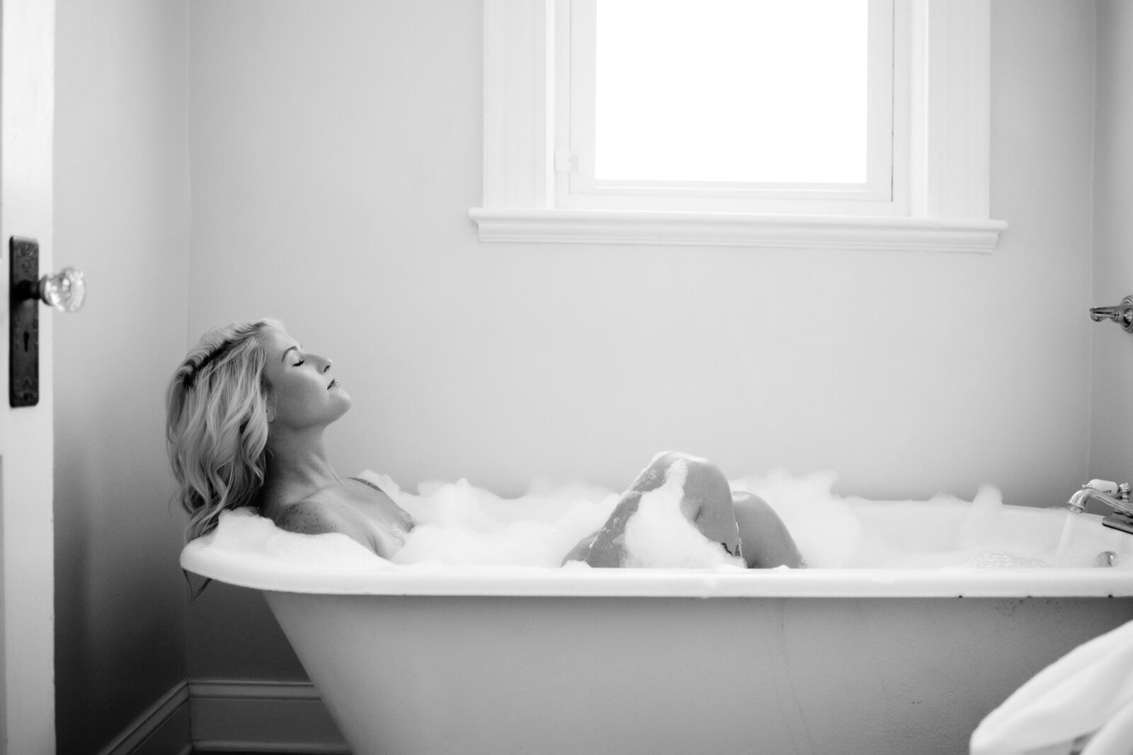 Black and white boudoir photo of woman in bathtub