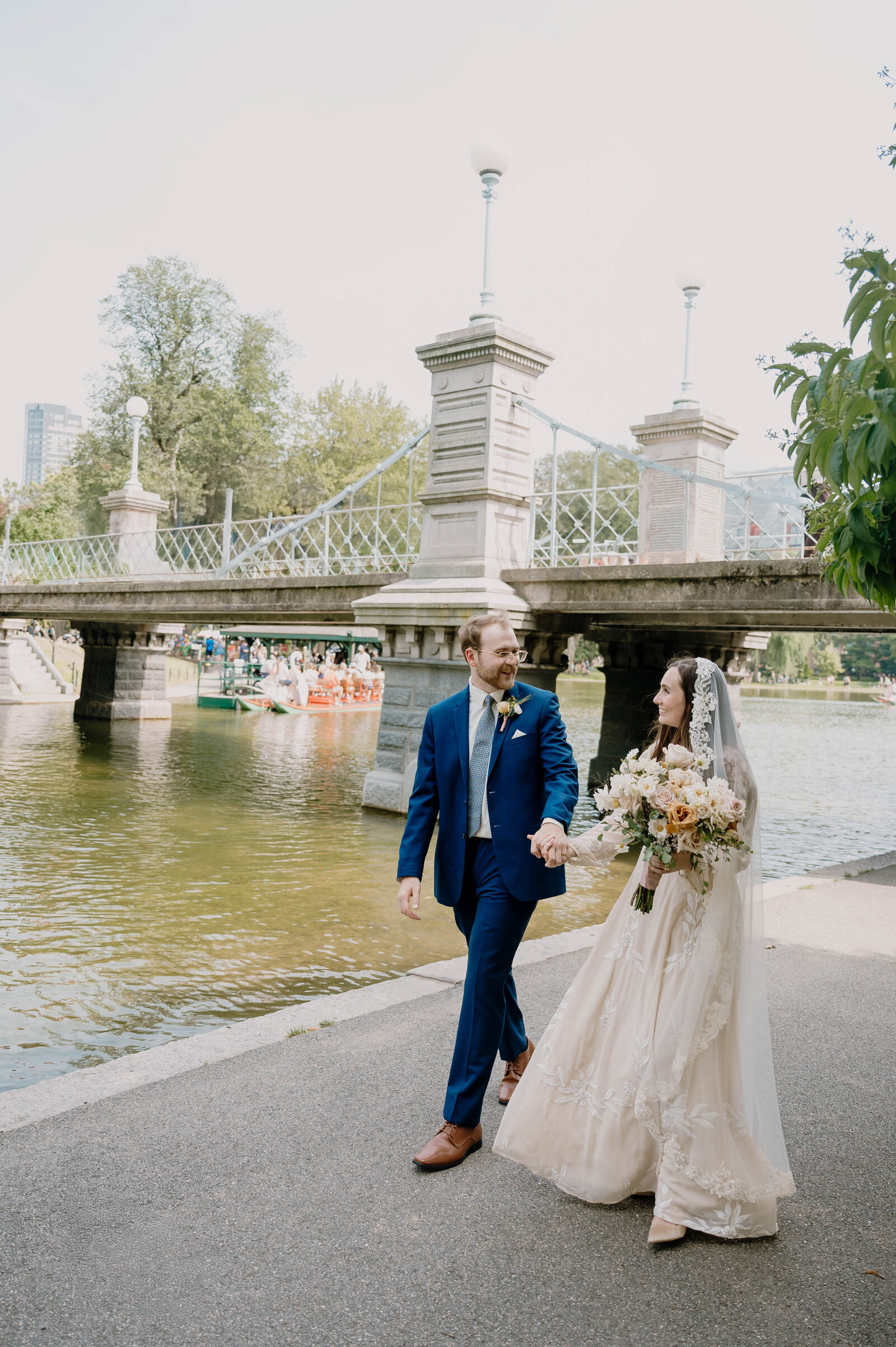 Bride and Groom walking hand in hand through Boston Public Gardens after their Church Ceremony