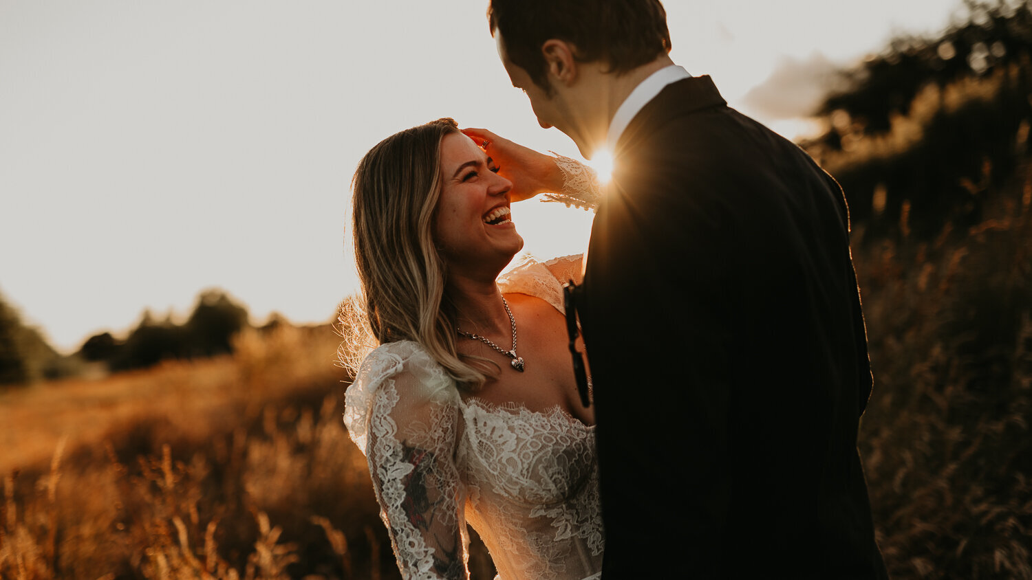 A couple kiss in the sunset at Willow Marsh Farm wedding venue.