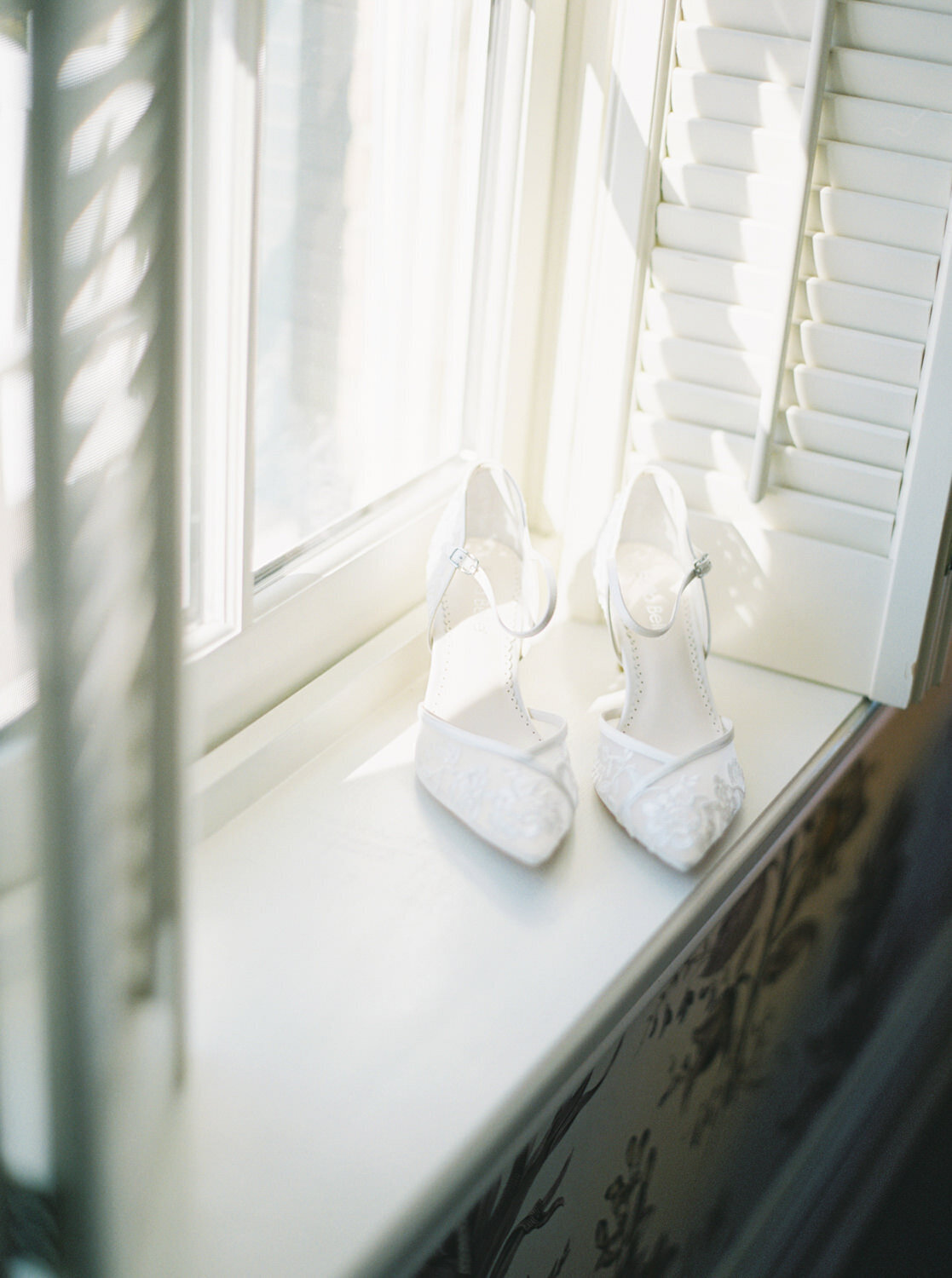 Bella Belle Wedding Shoes sit on a window sill in sunlight.