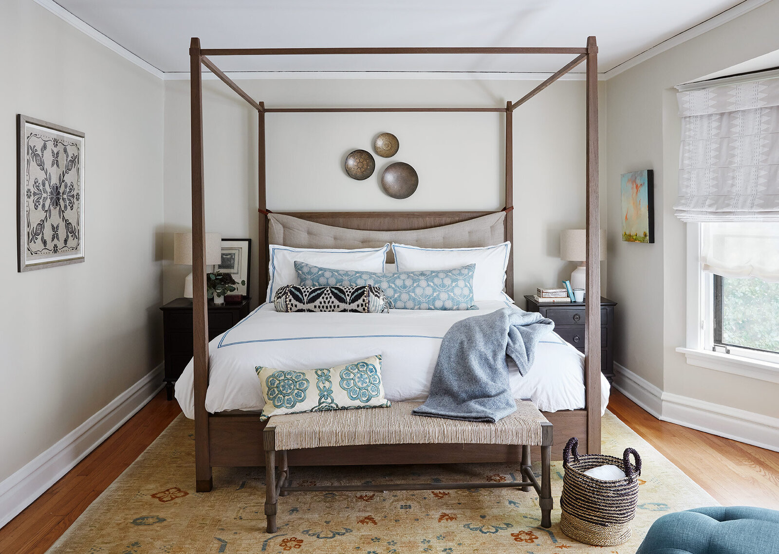 Canopy bed with white comforter and blue pillows