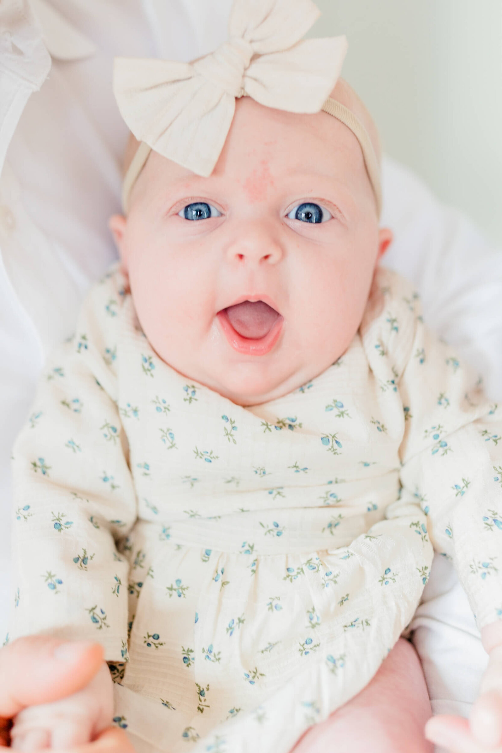 Newborn with a bow on her head smiles