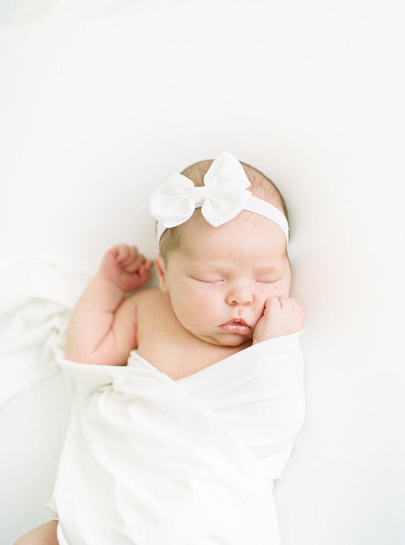 Newborn baby in white bow