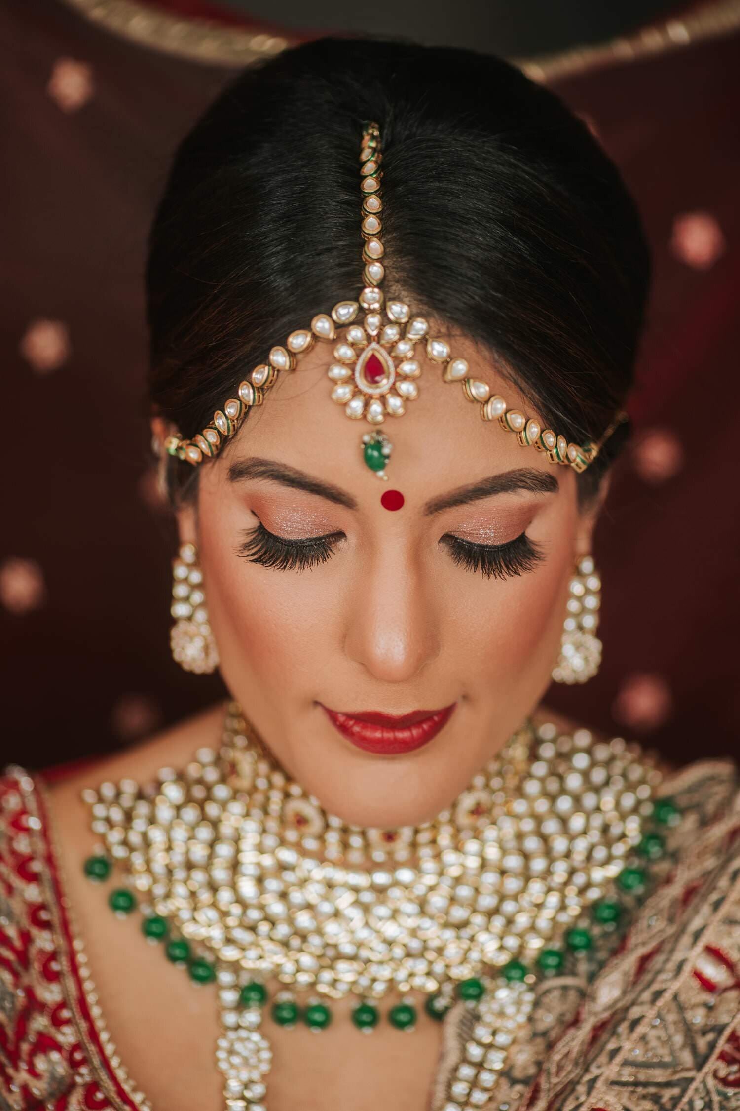 Bridal portrait with a kundan maang tikka, emerald choker, and red bridal veil before a Lehigh Valley Indian wedding