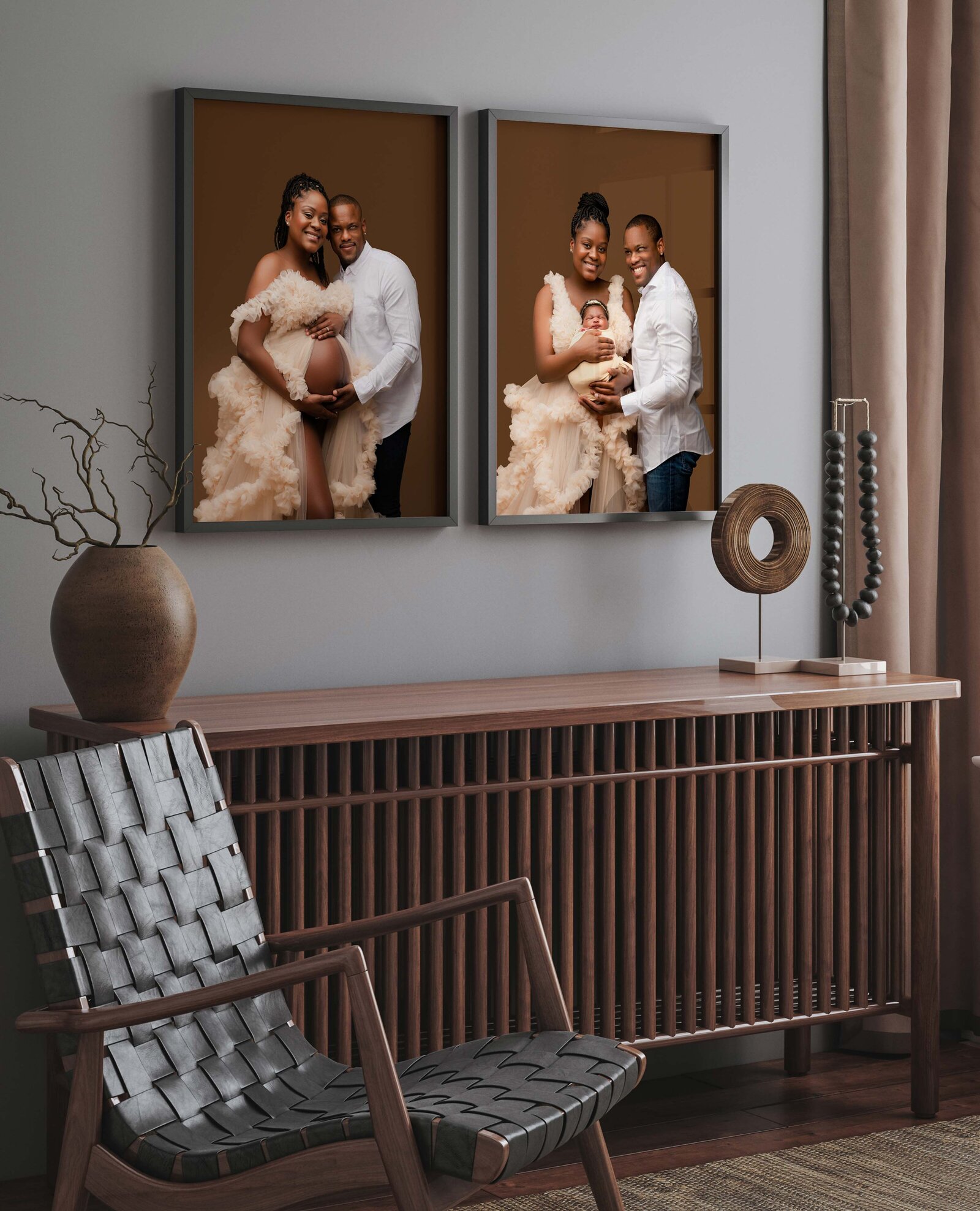 Room featuring two framed family photos on a wall, showcasing a couple with their baby captured by a Charlotte newborn photographer. A chair with a woven seat is placed beside a wooden cabinet, which has decorative items, including a sculpture and a dried plant arrangement.