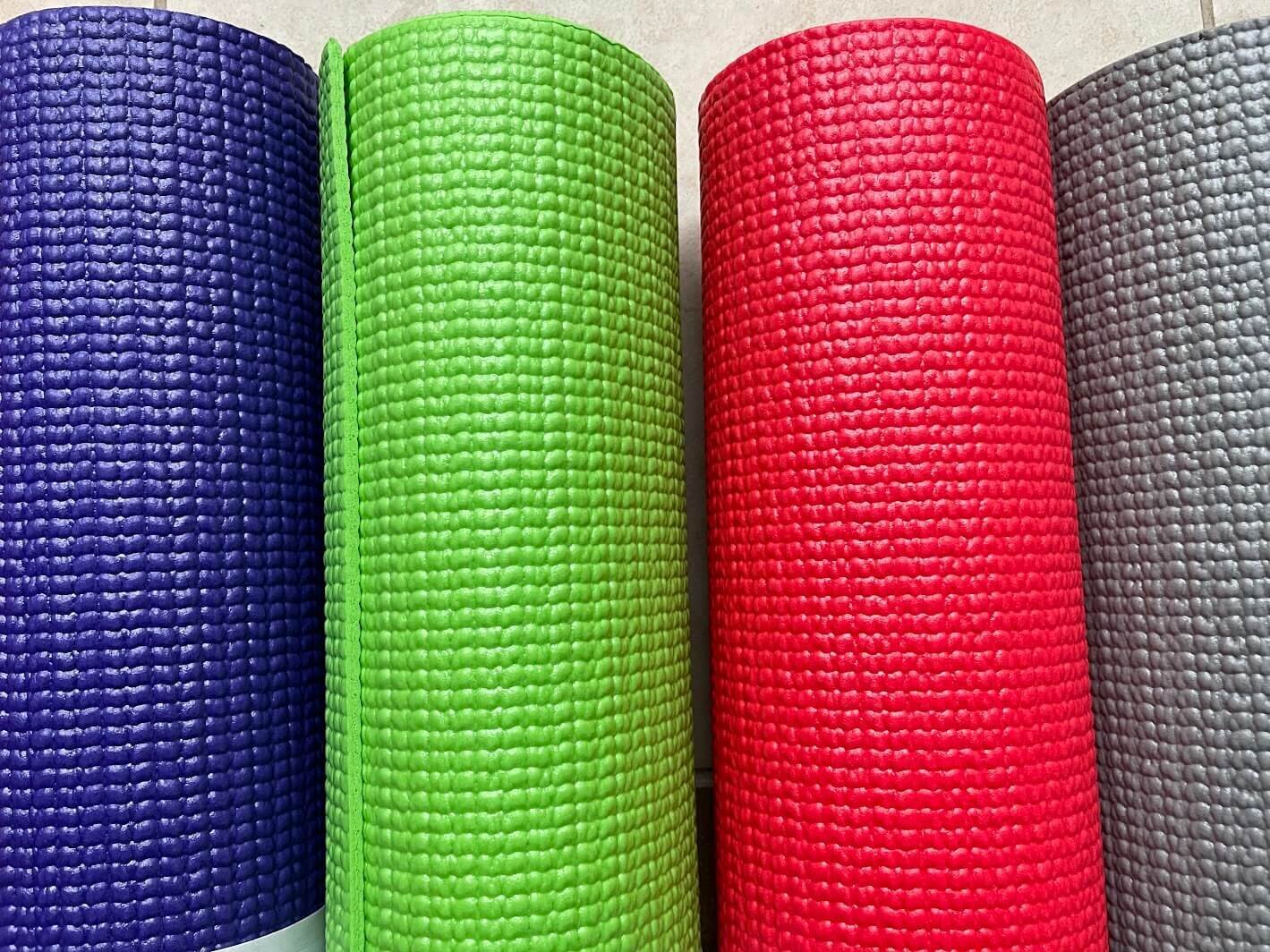 Four colorful yoga mats rolled up — banner image for online yoga classes for sore knees