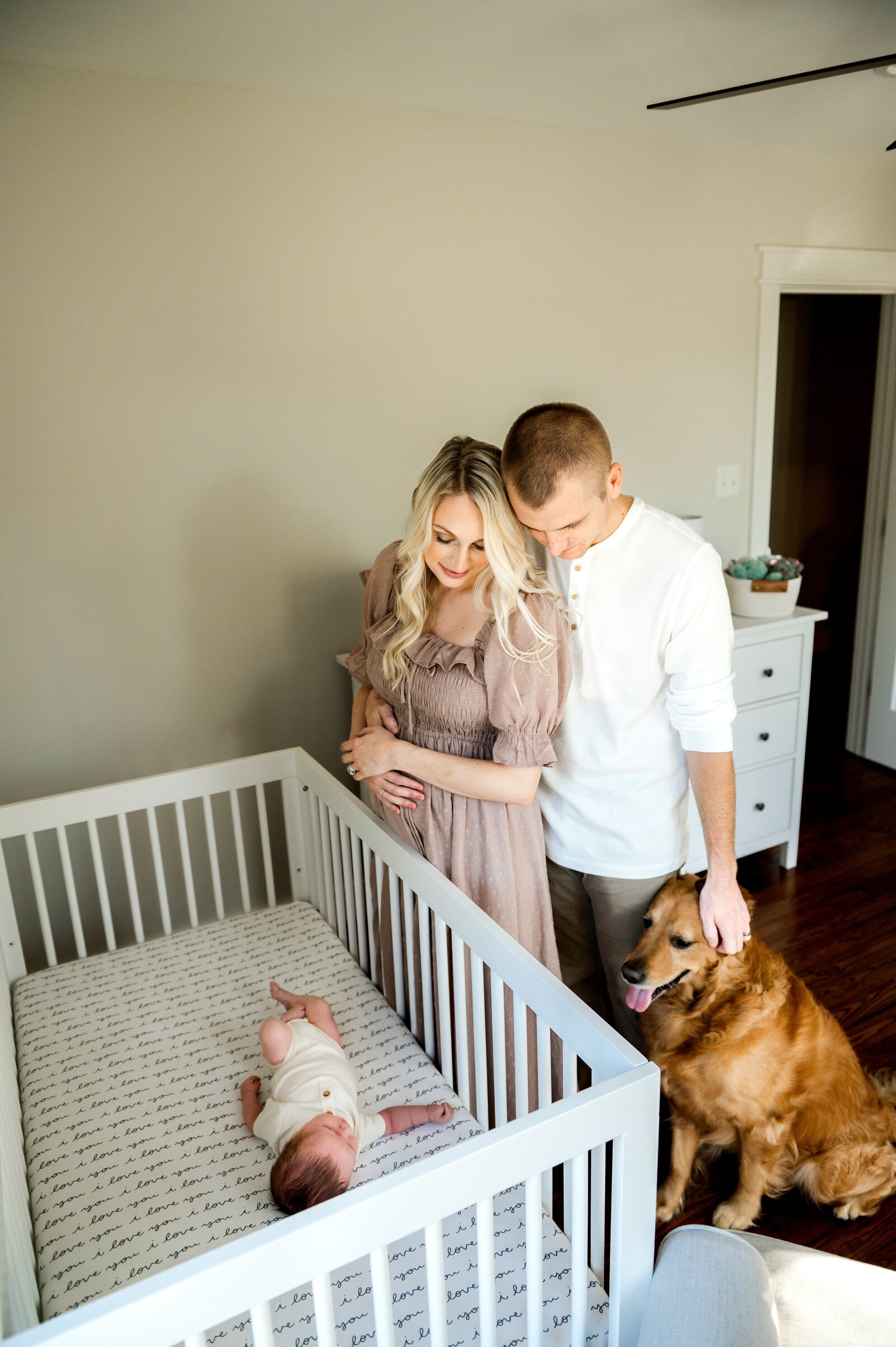 mom and dad looking at newborn baby in his crib