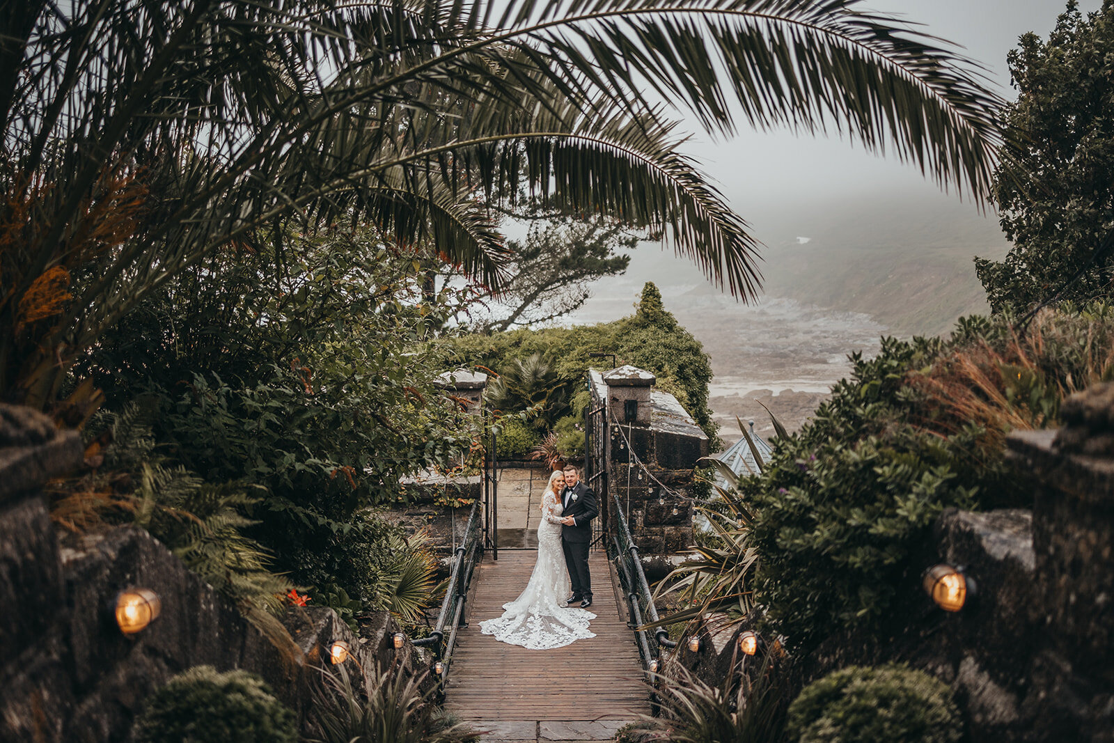 newlywed couple pose by ocean