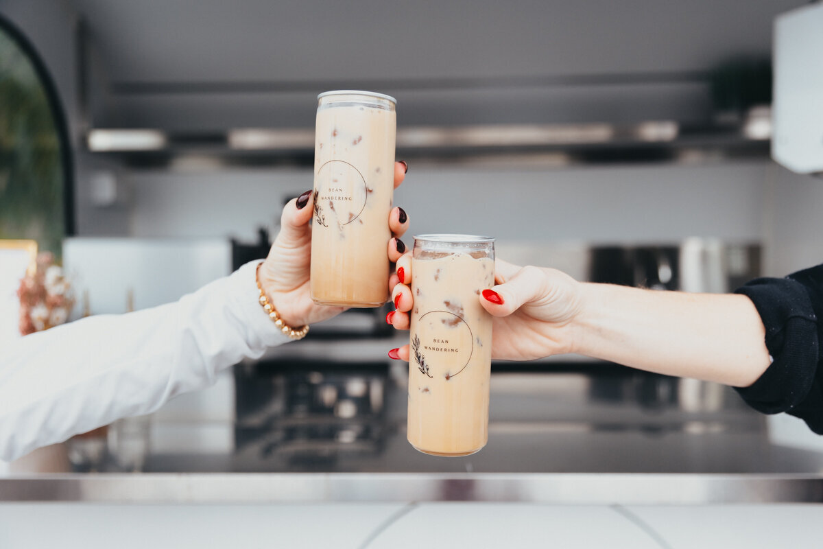 two hands clinking together iced coffee beverages