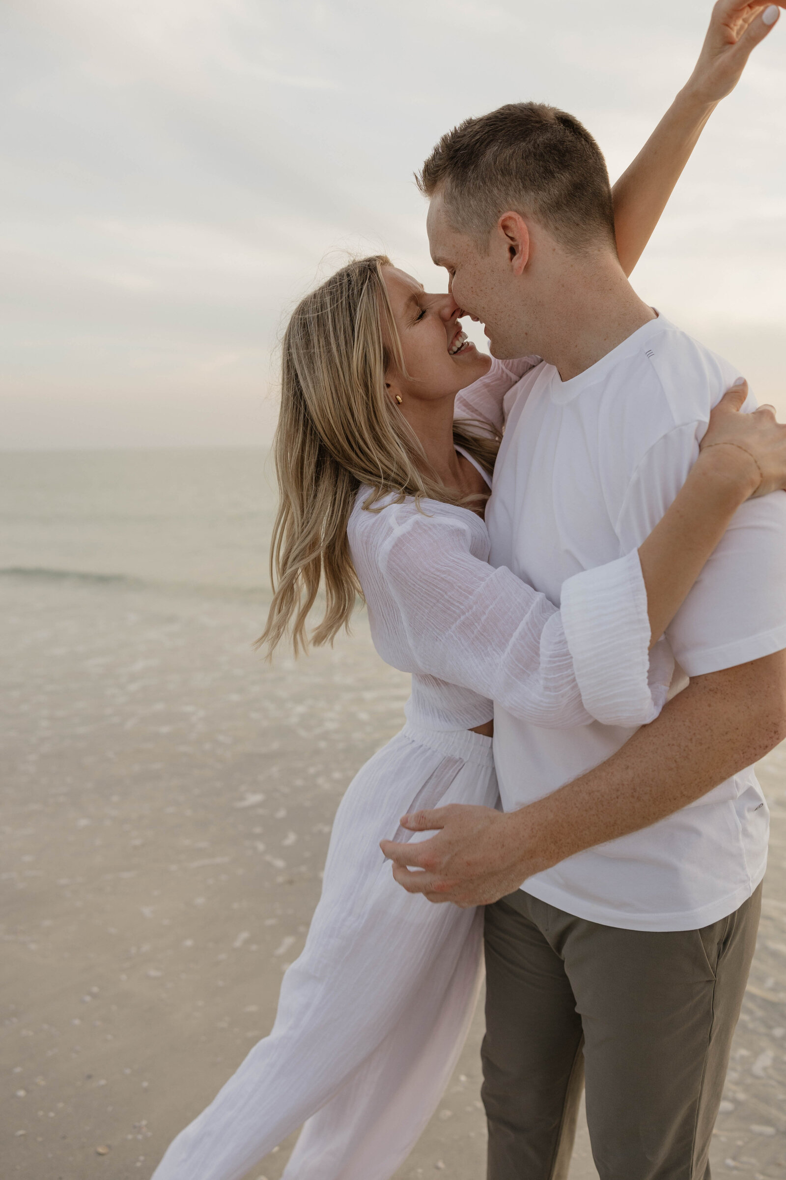 A romantic couple laughing during a candid engagement photography shoot.