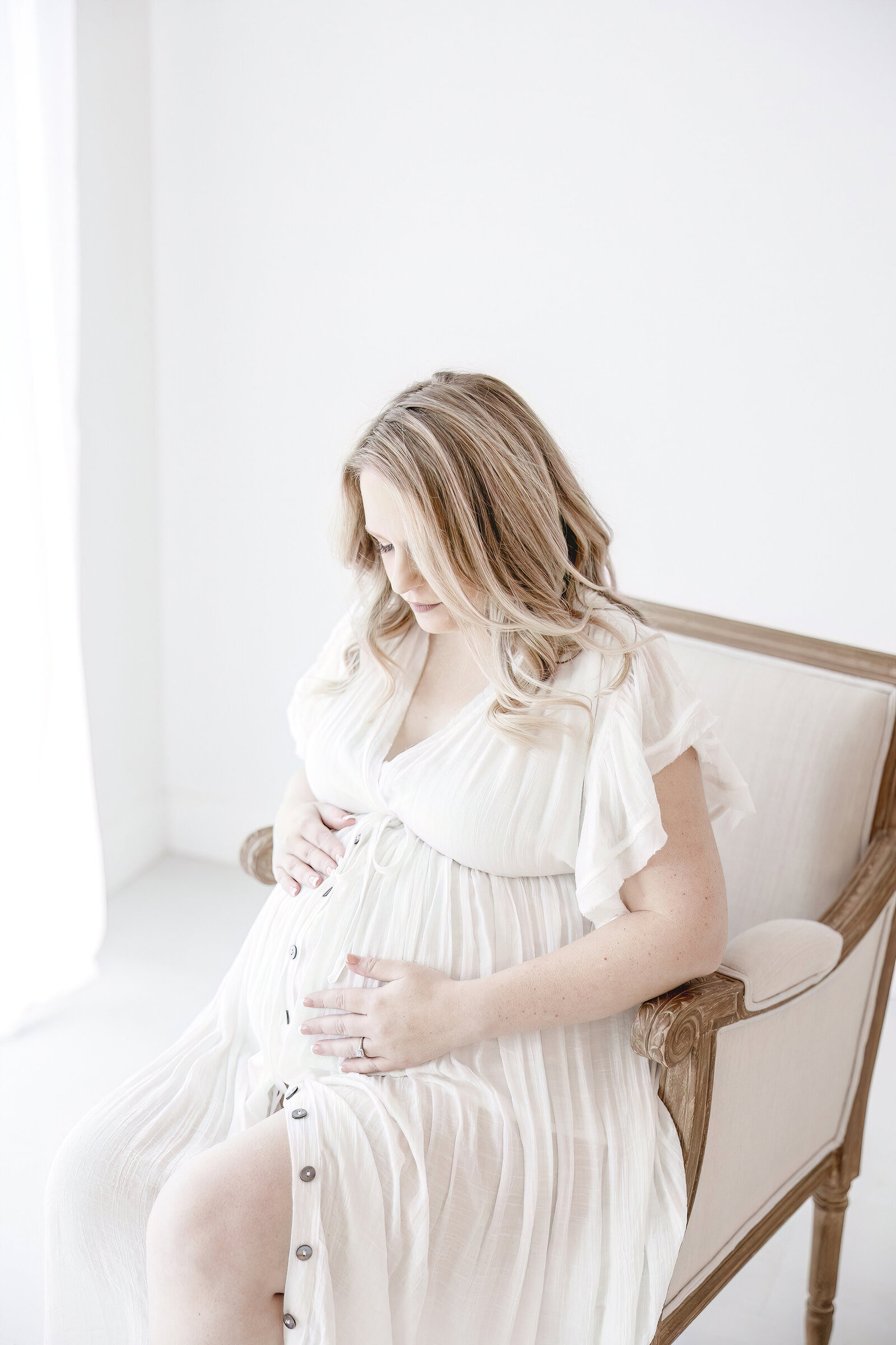 Pregnant woman in white dress sitting in chair