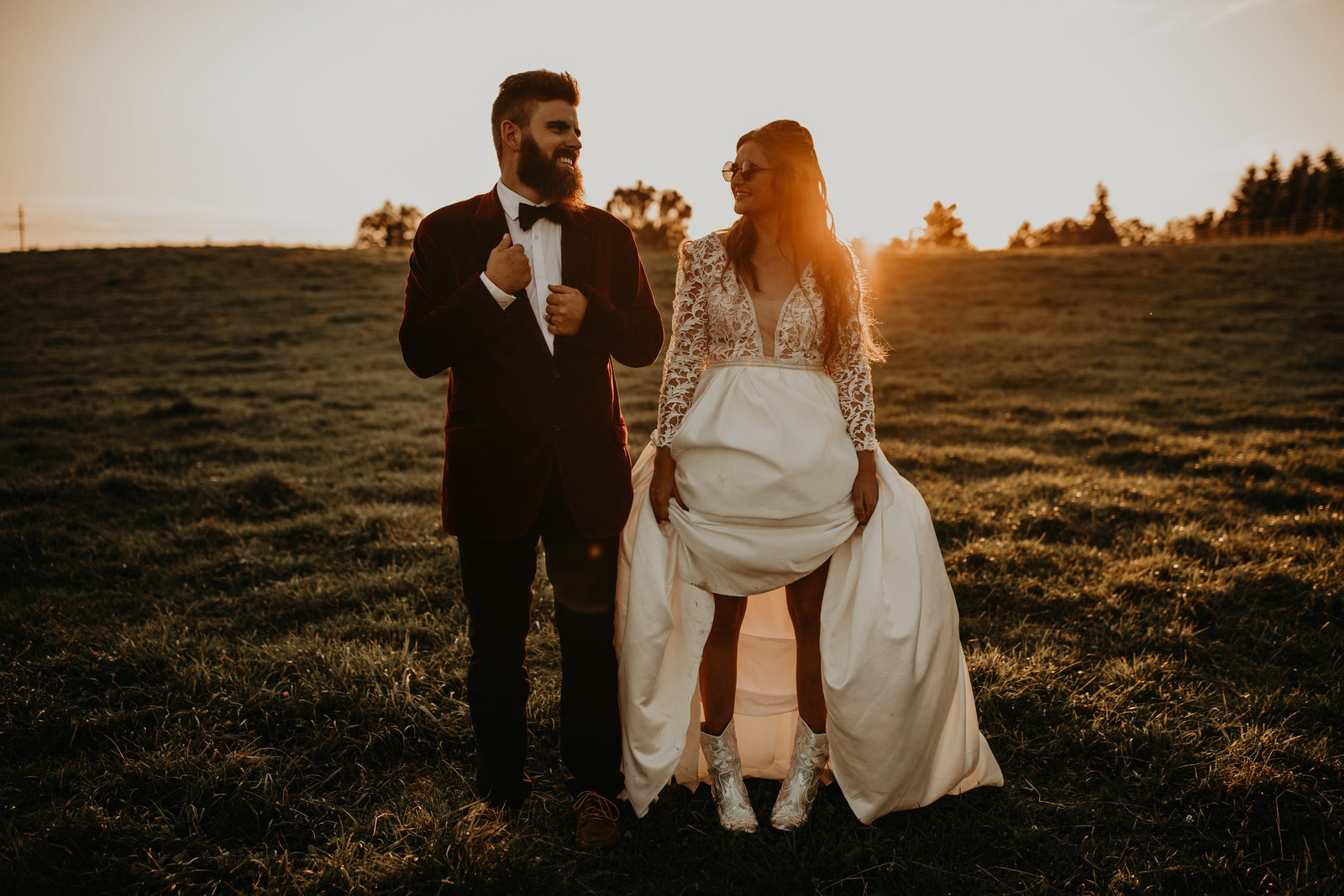 bride and groom smiling at each other while standing in field