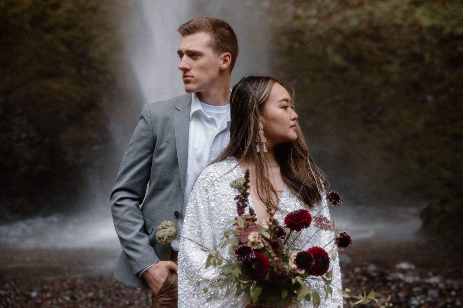 a couple in front of a large waterfall for their elopement