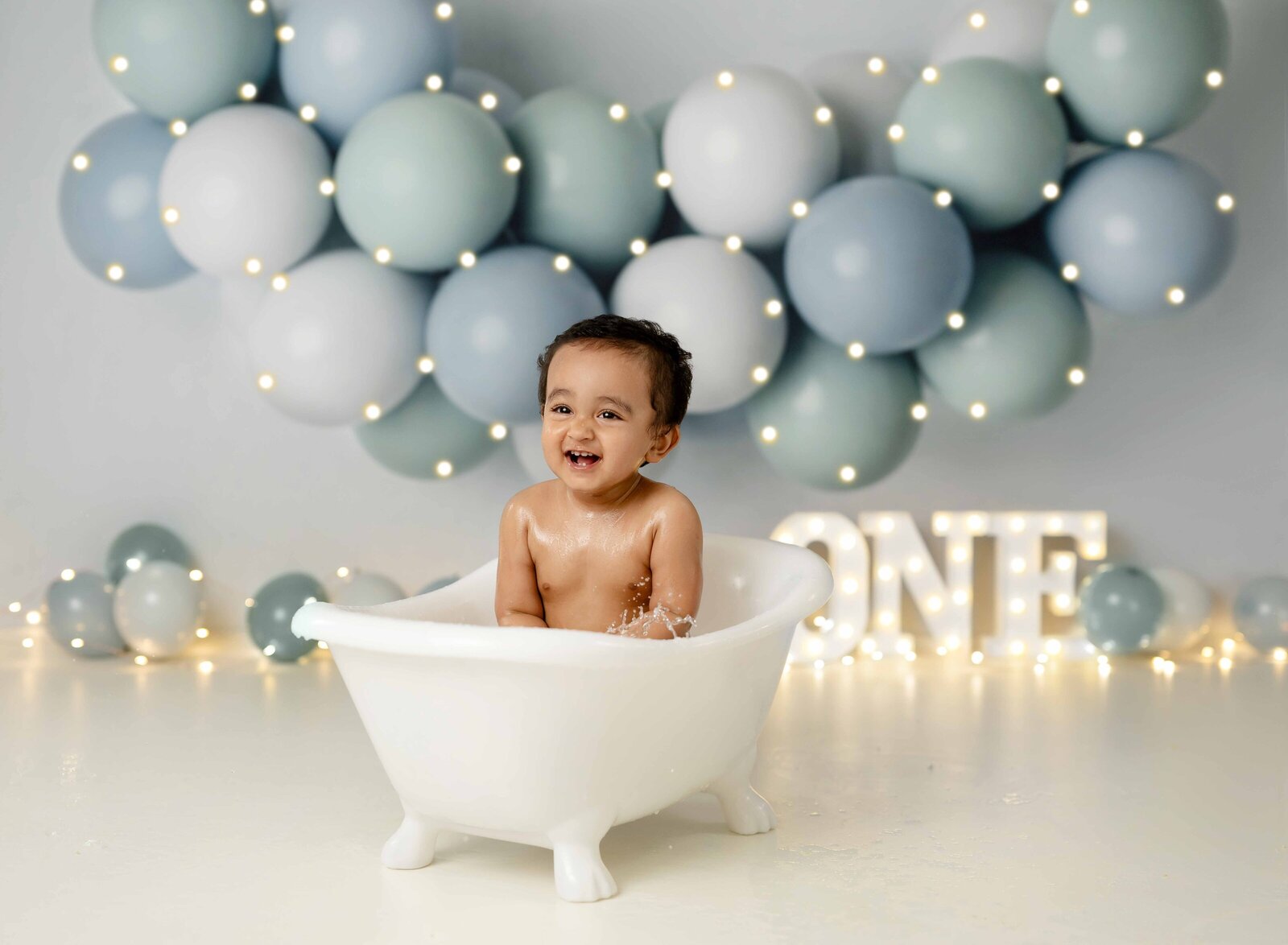 Baby cleaning up in tiny bathtub after getting messy smashing a cake.