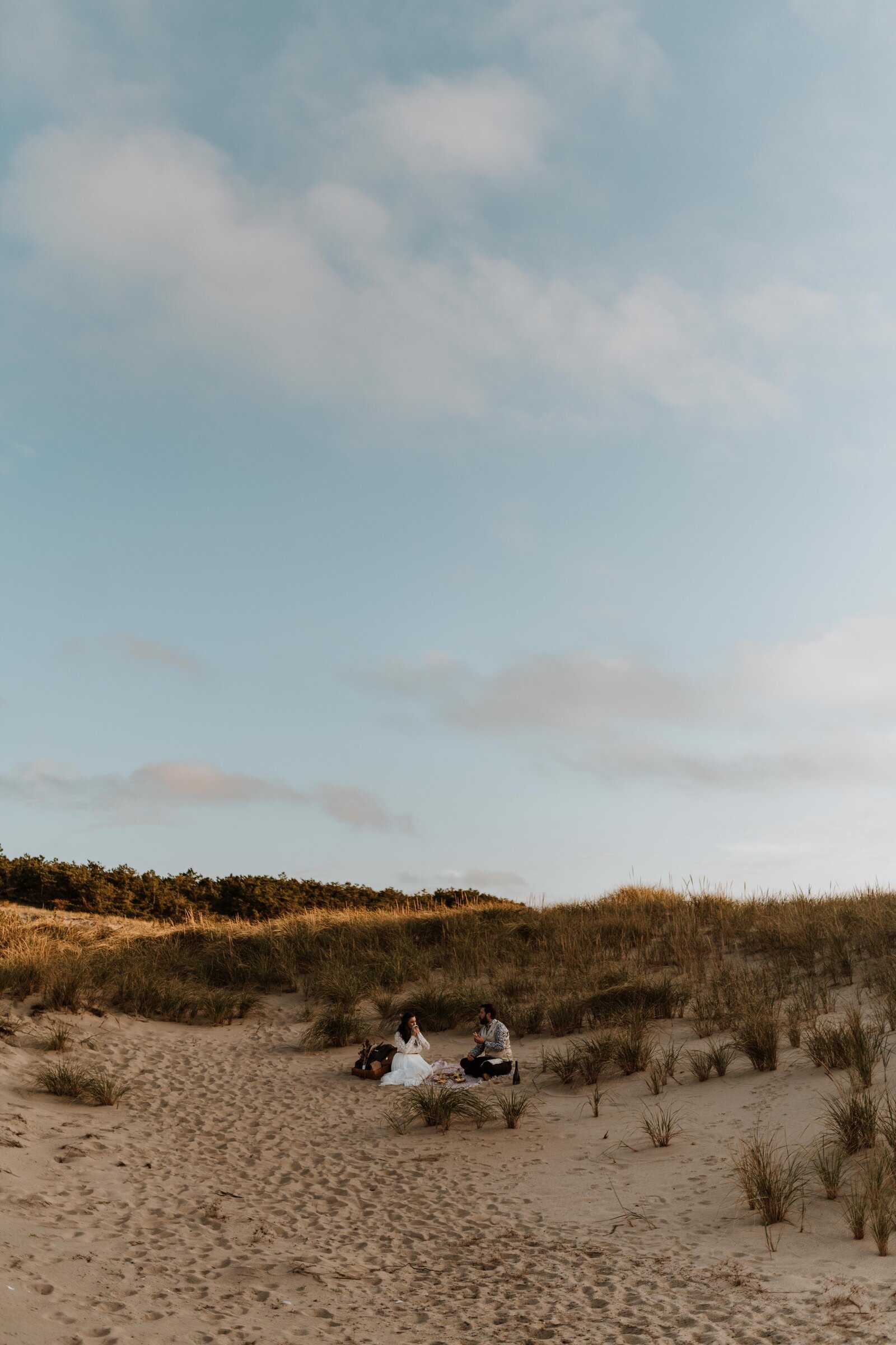 Eloping couple sitting together in  sand dunes