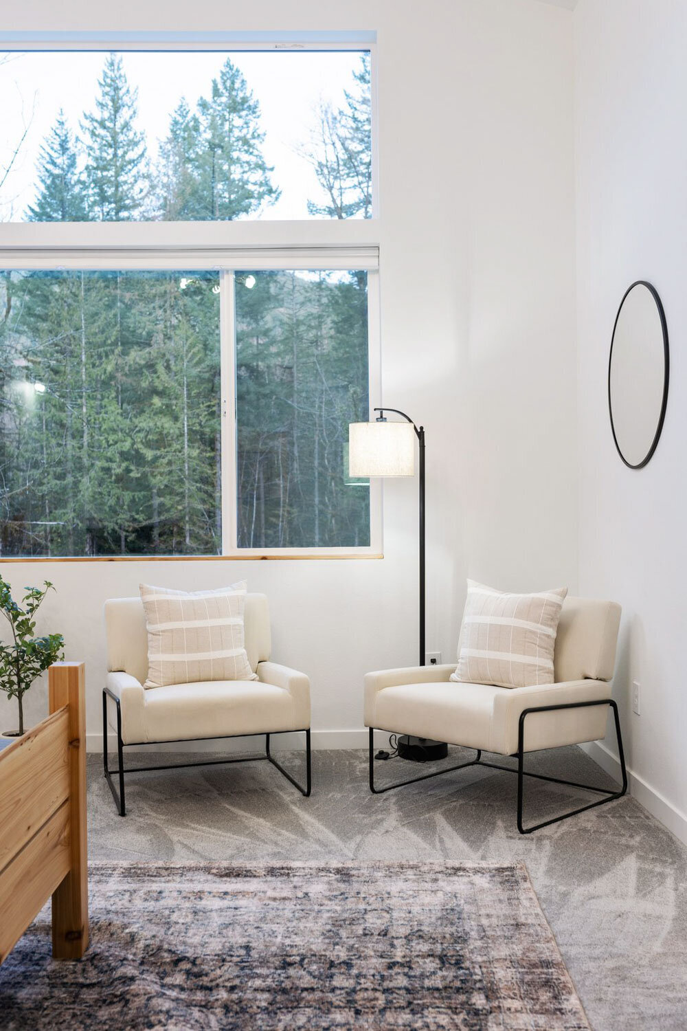 Cozy corner with two cream chairs, large window, and soft lighting