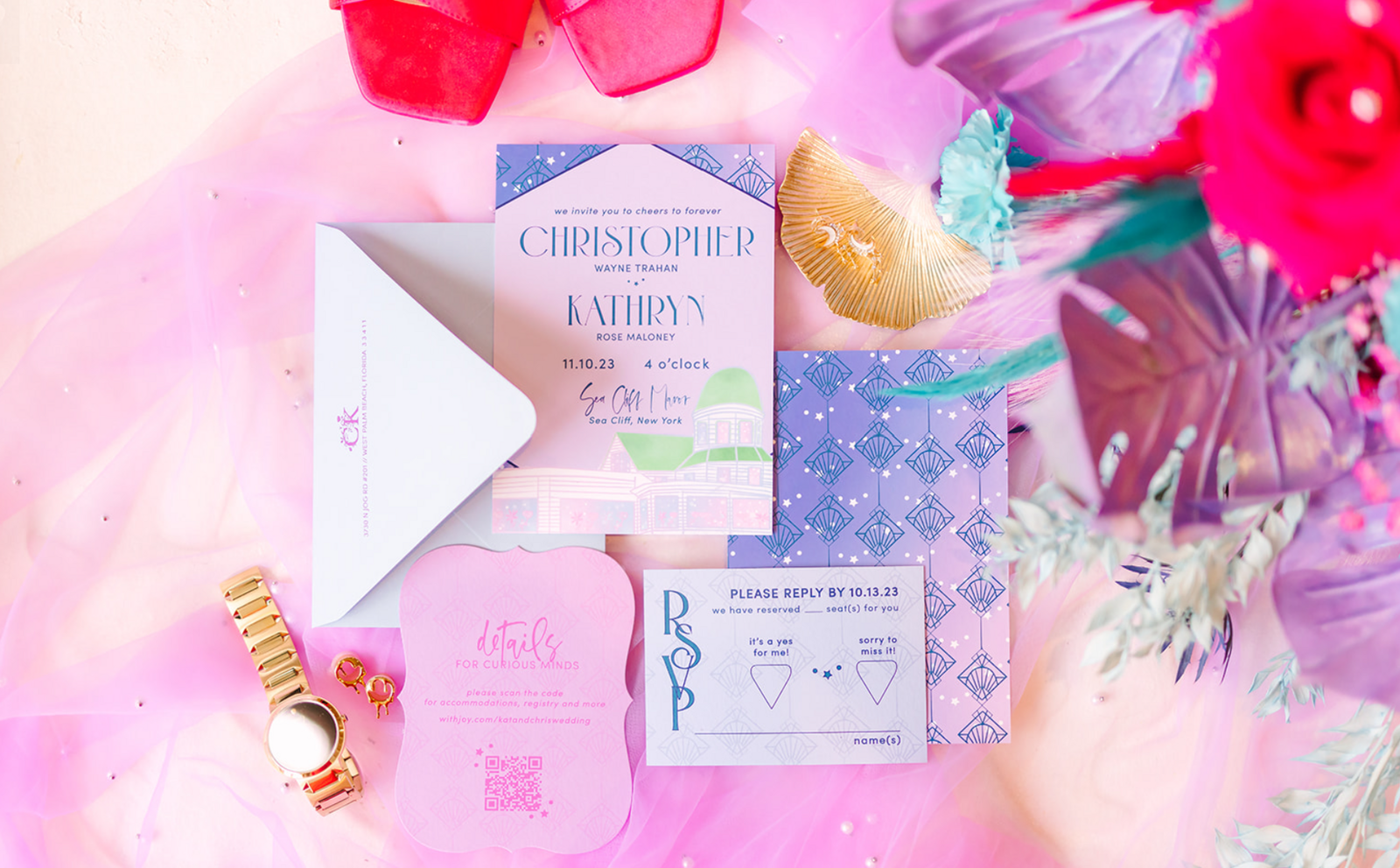 A wedding invitation flat lay featuring a watercolor venue illustration of Sea Cliff Manor and art deco patterns.