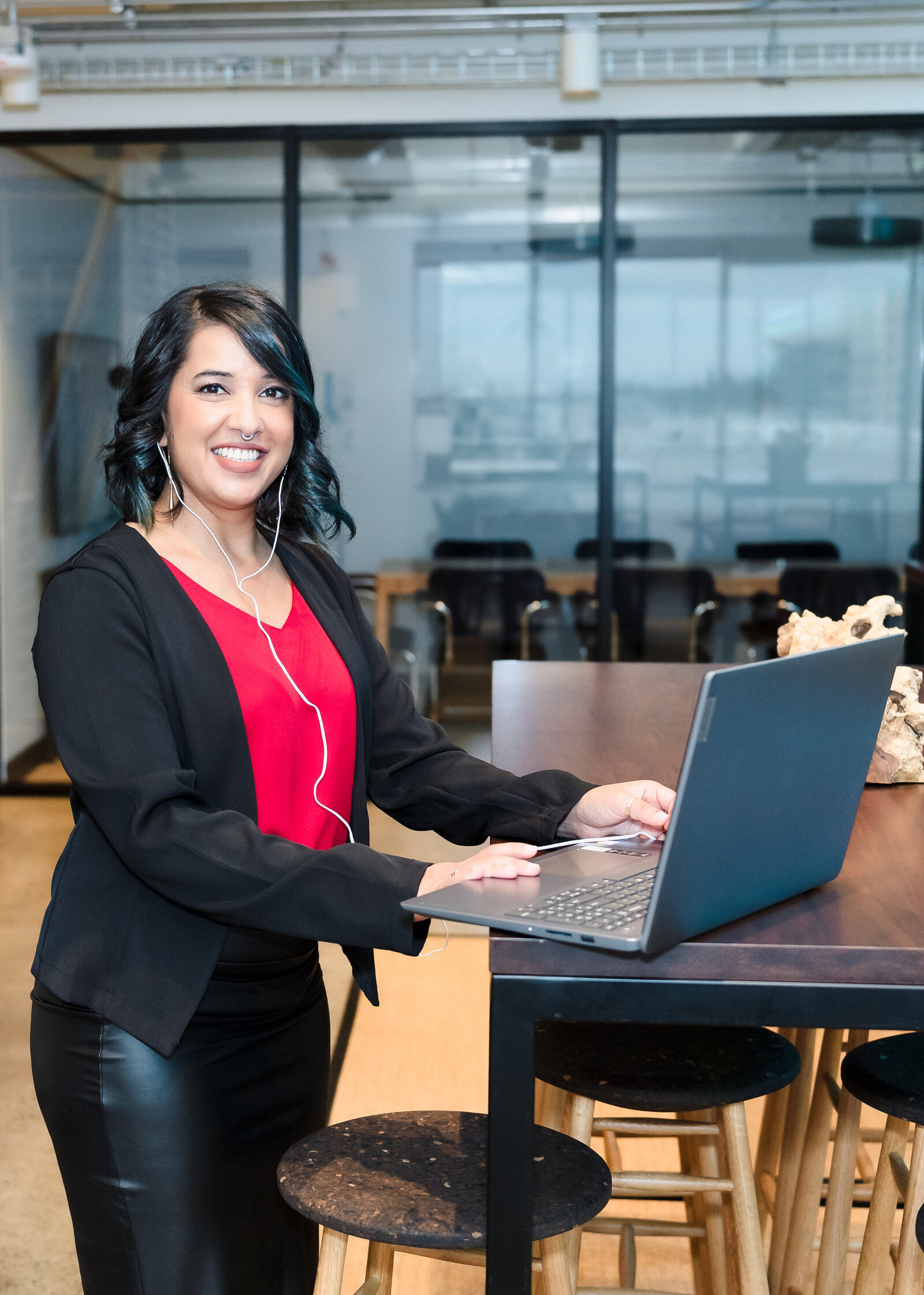 Business Coach stands tall, laptop in her desk, and smiles