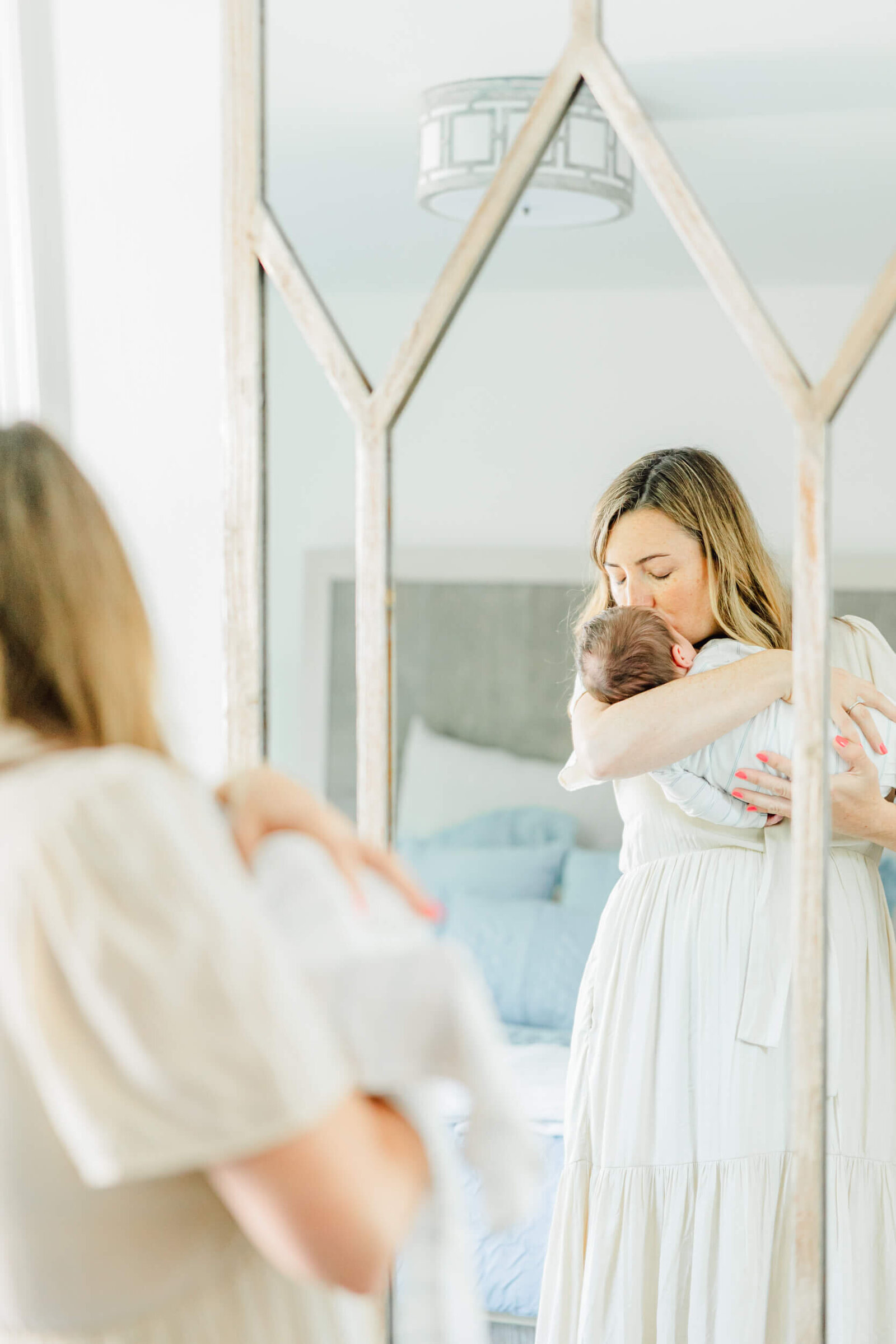 Mirror reflection showing mom giving her newborn baby a kiss